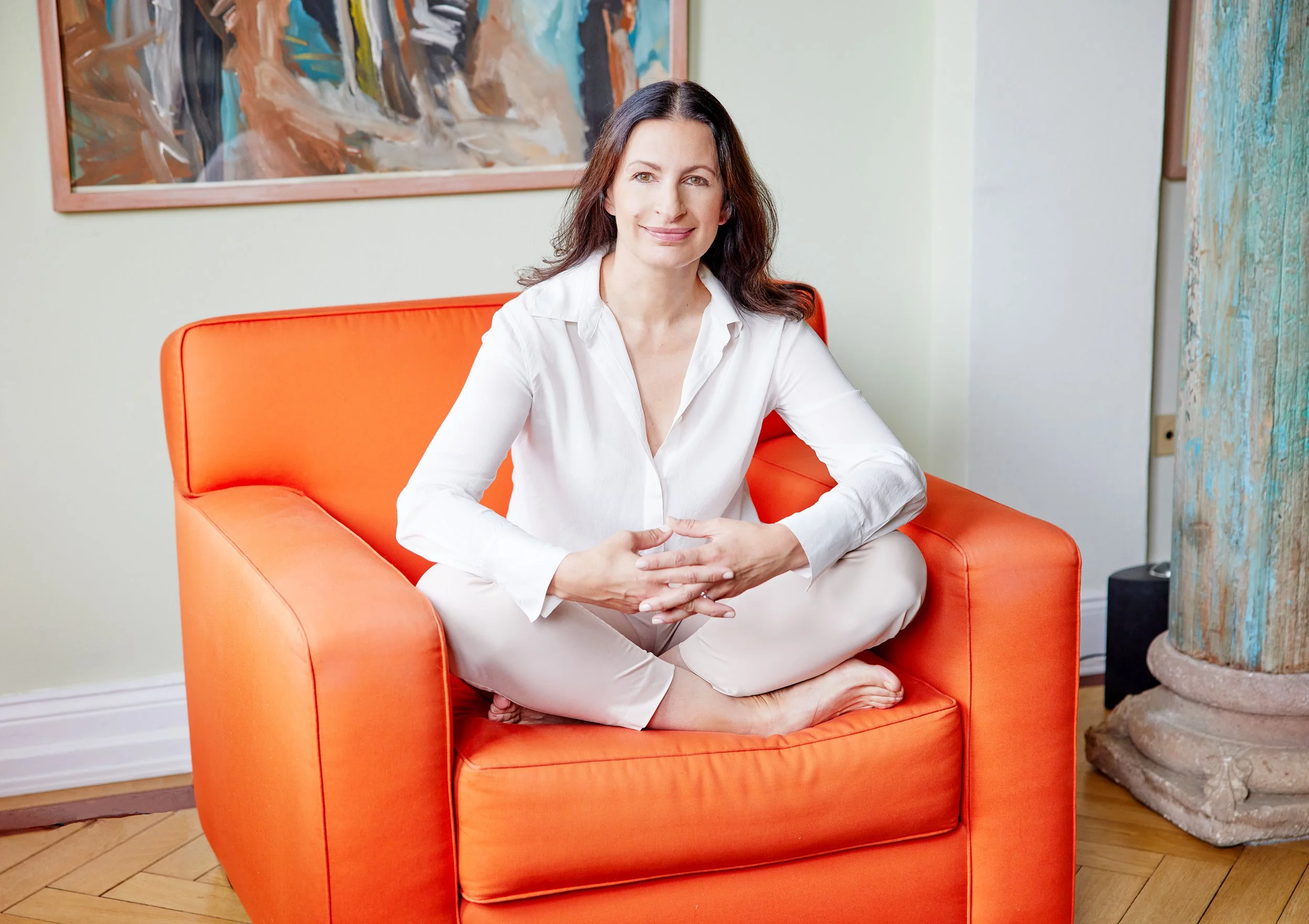Claudia Nacci, systemischer Coach für Ärztinnen, sitzend auf einem orangefarbenen Sessel – spezialisiert auf Führung, Kommunikation und Selbstsicherheit im Klinik- und Praxisalltag