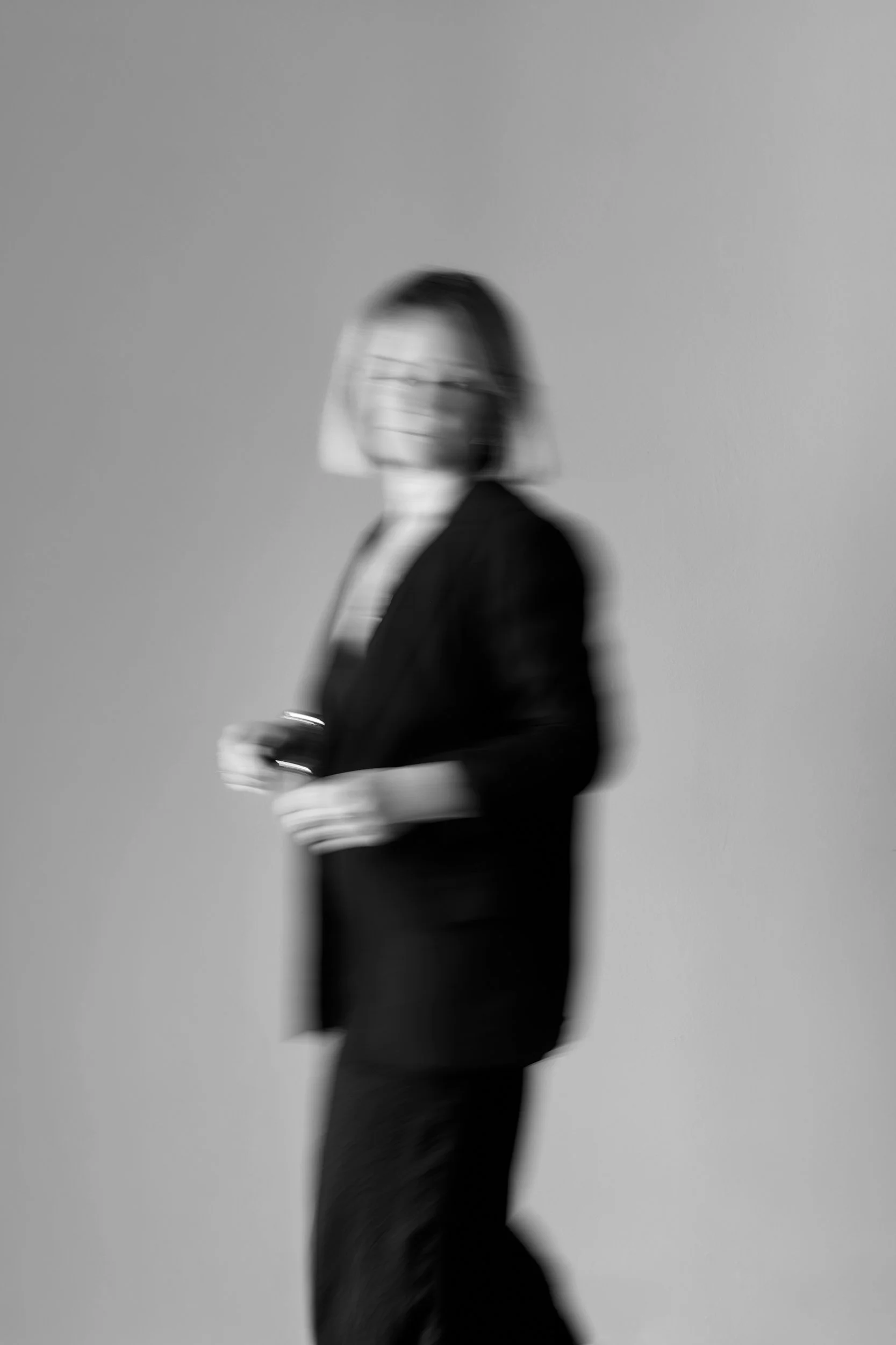 Sort-hvid foto af en person i profil, der går, slør foran ansigtet, blurrer.