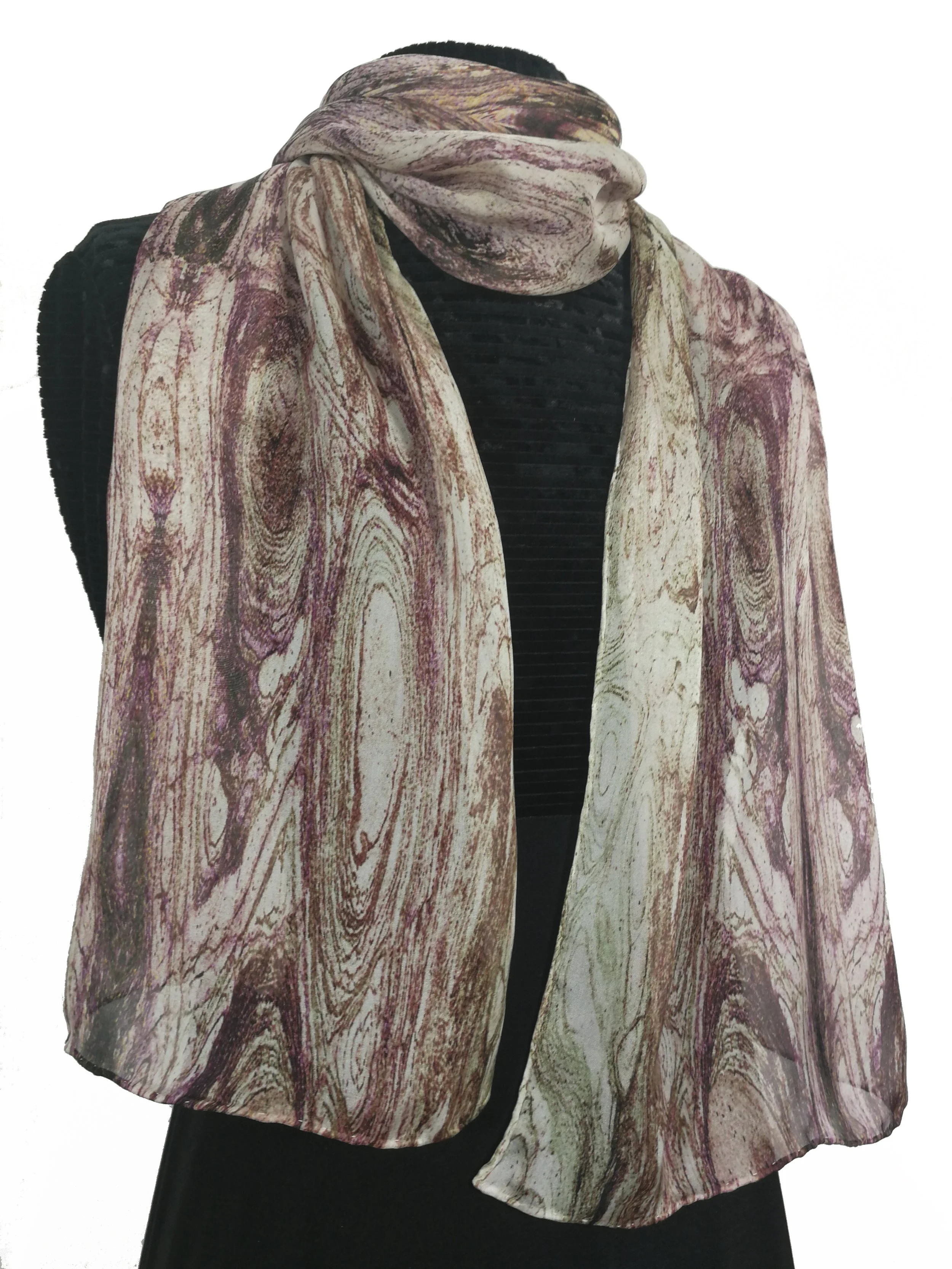 A mannequin wearing a black dress and a large silk scarf with a marble pattern in shades of white, pink, and burgundy.