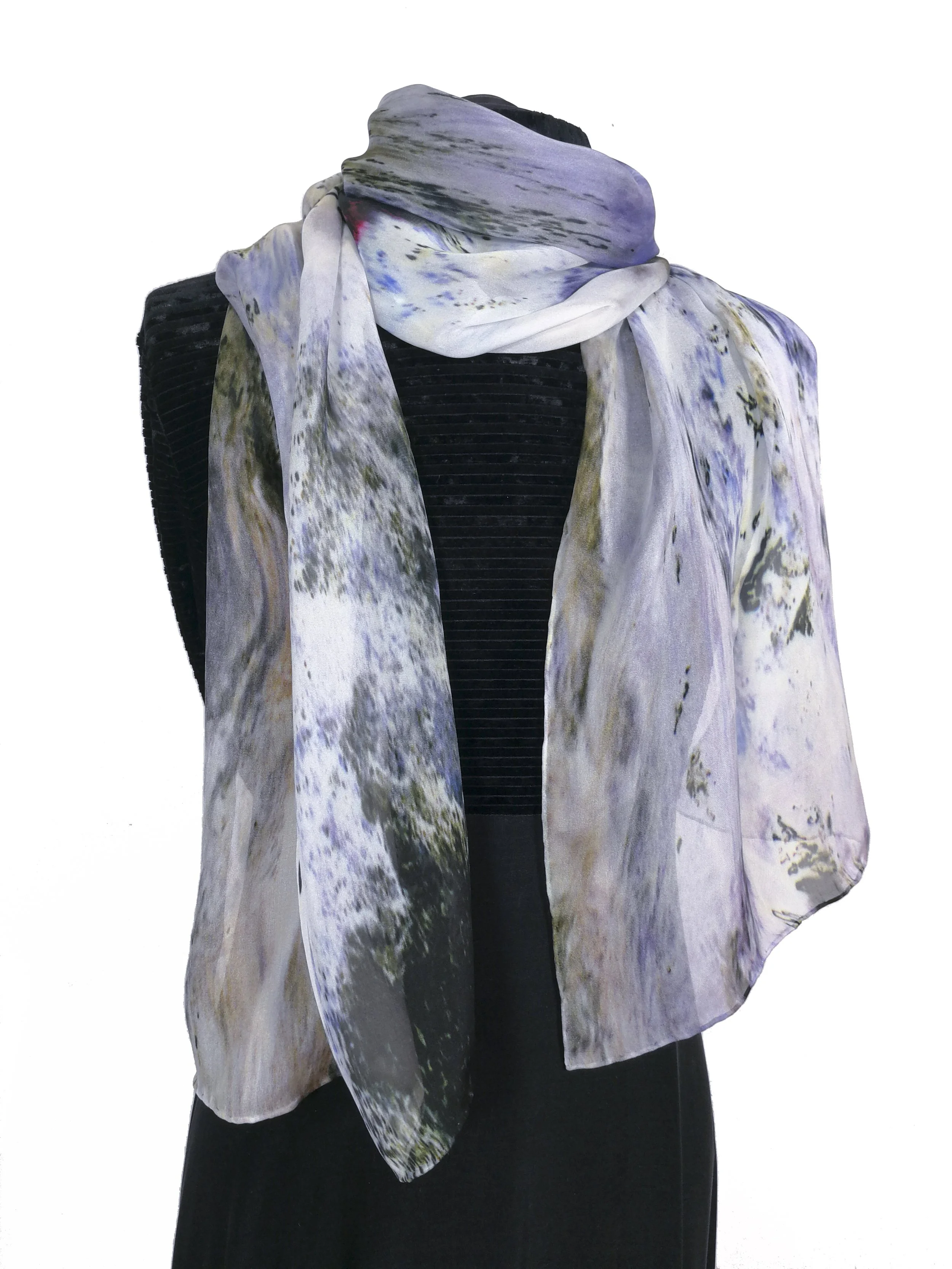 A person wearing a black top with a colorful, abstract, patterned scarf around their neck.