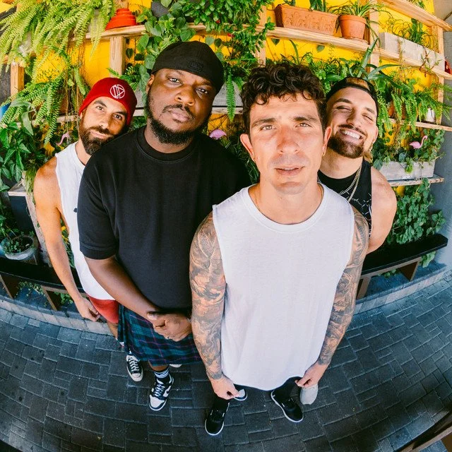 Five men posing together outdoors in front of leafy bushes with text overlay 'FELICITY' and 'HOLD ON'