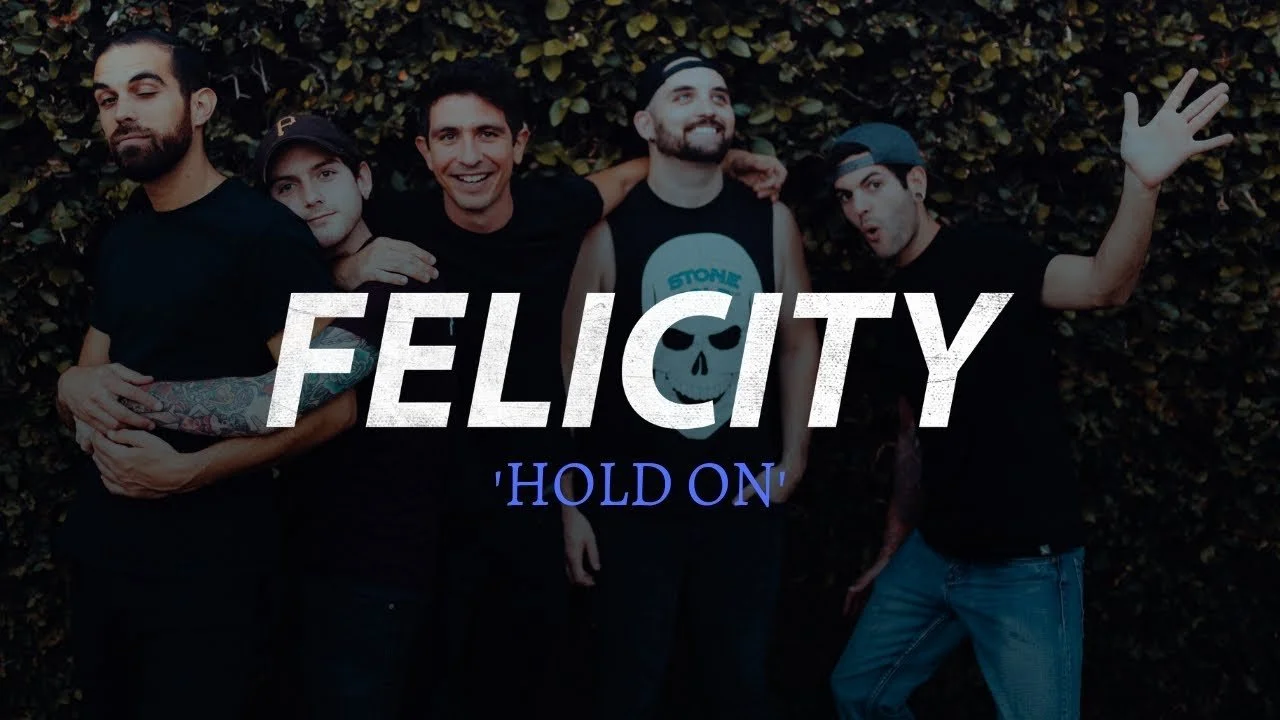 Five men posing together outdoors in front of leafy bushes with text overlay 'FELICITY' and 'HOLD ON'