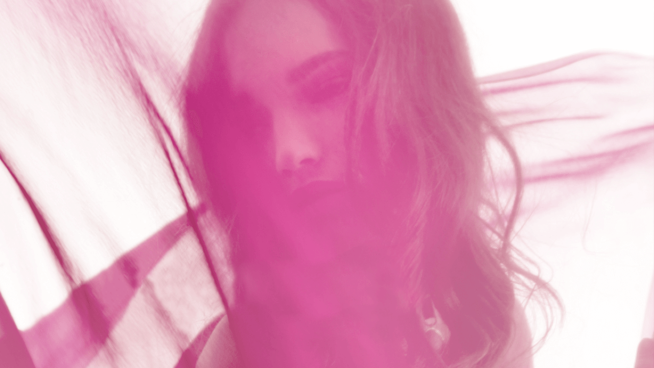 Porträt einer Frau mit longem, lockigem Haar, halb im Schatten, mit pinkem Farbfilter.