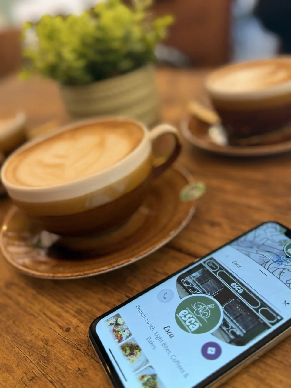 A woman with long dark hair wearing a light pink blazer and white shirt, smiling while holding a silver laptop against a plain white background.