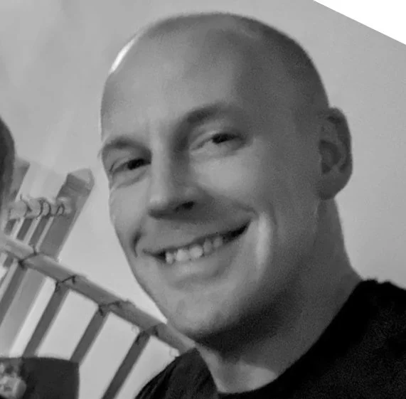 Black and white photo of a smiling young man with short hair.