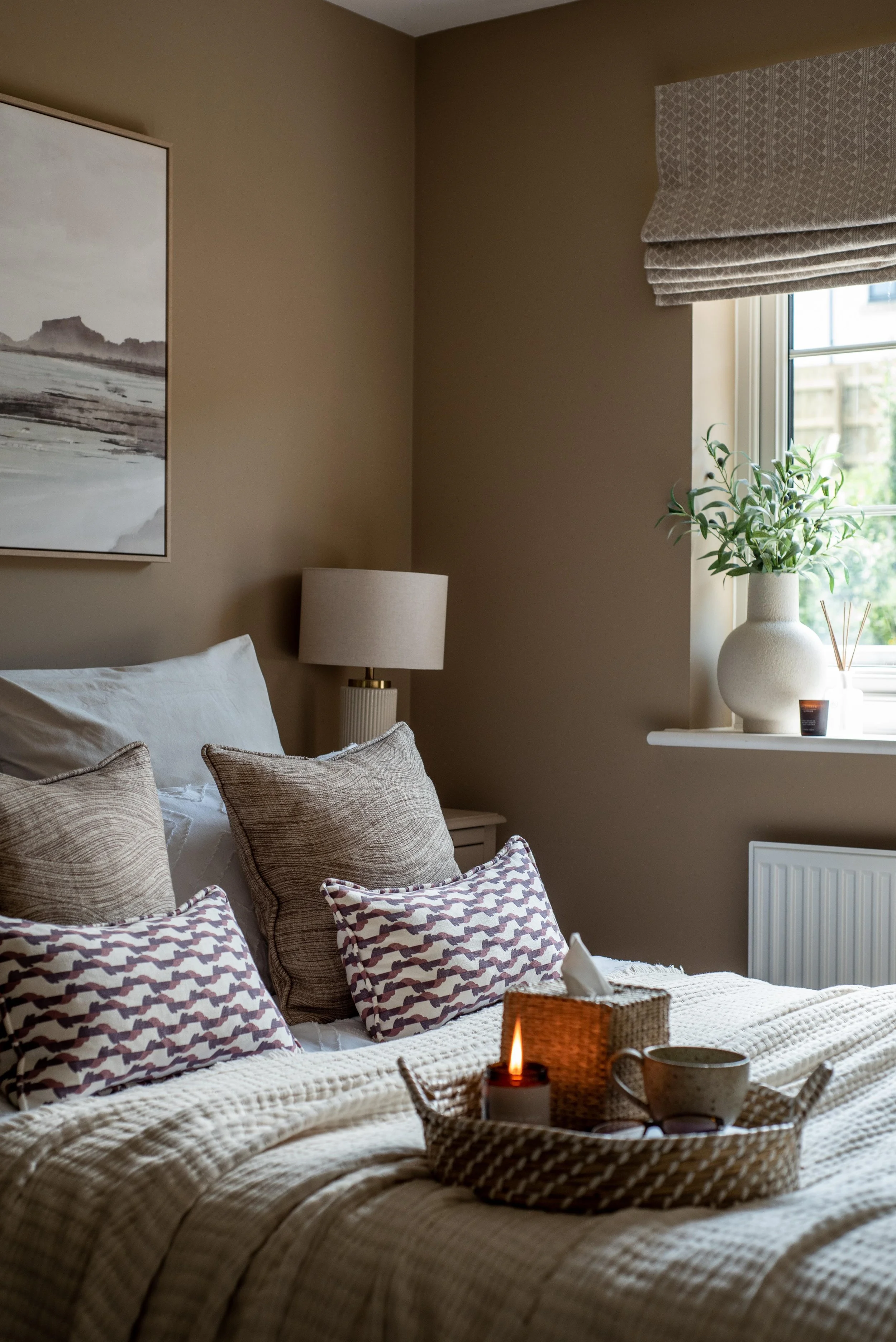 Cosy, warm guest bedroom with patterned cushions, neutral table lamps and linen throw. Inspired by the shapes and textures of the Cornish coastline.