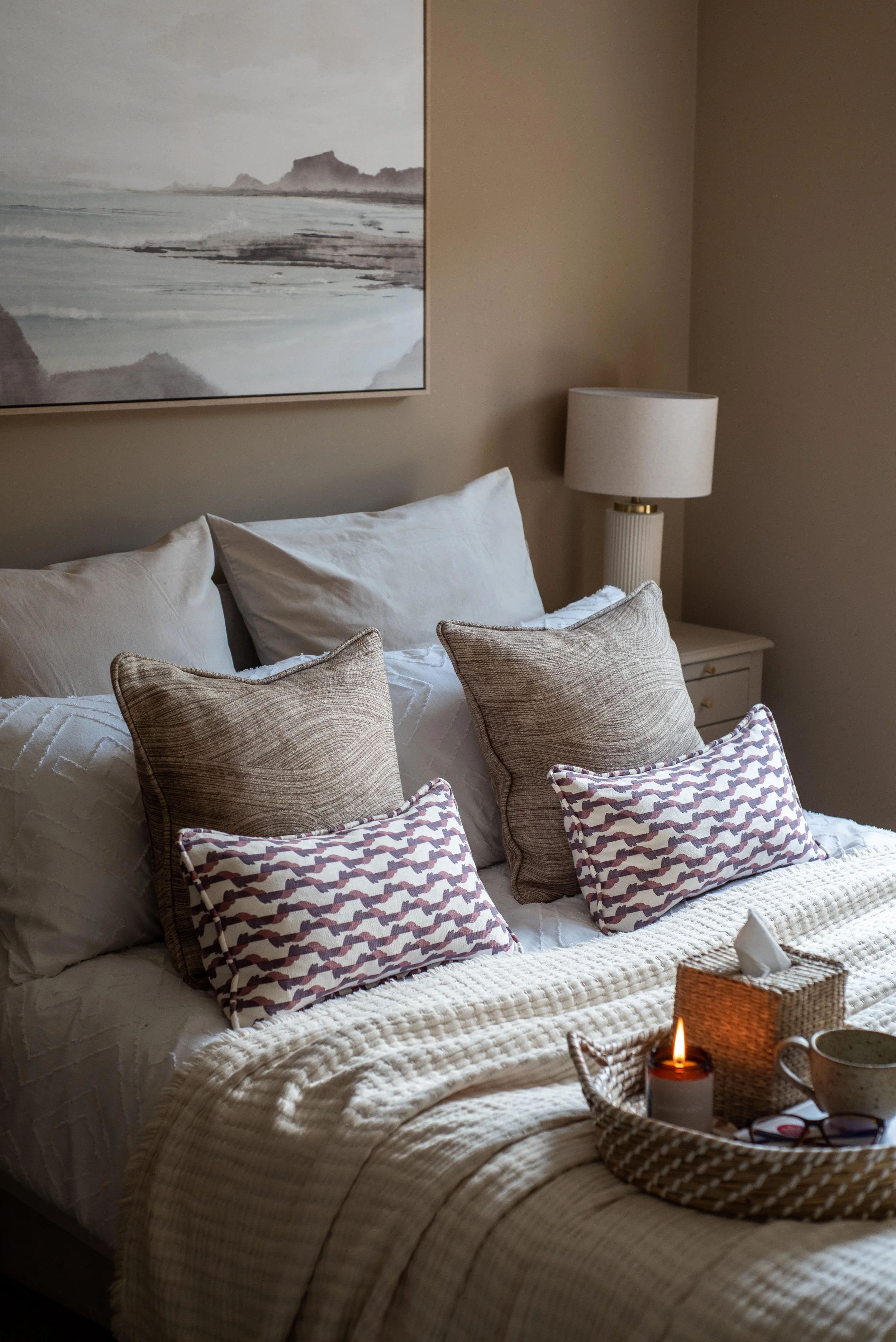 Coastal Cornish Bedroom with abstract seascape artwork and layered, patterned cushions.