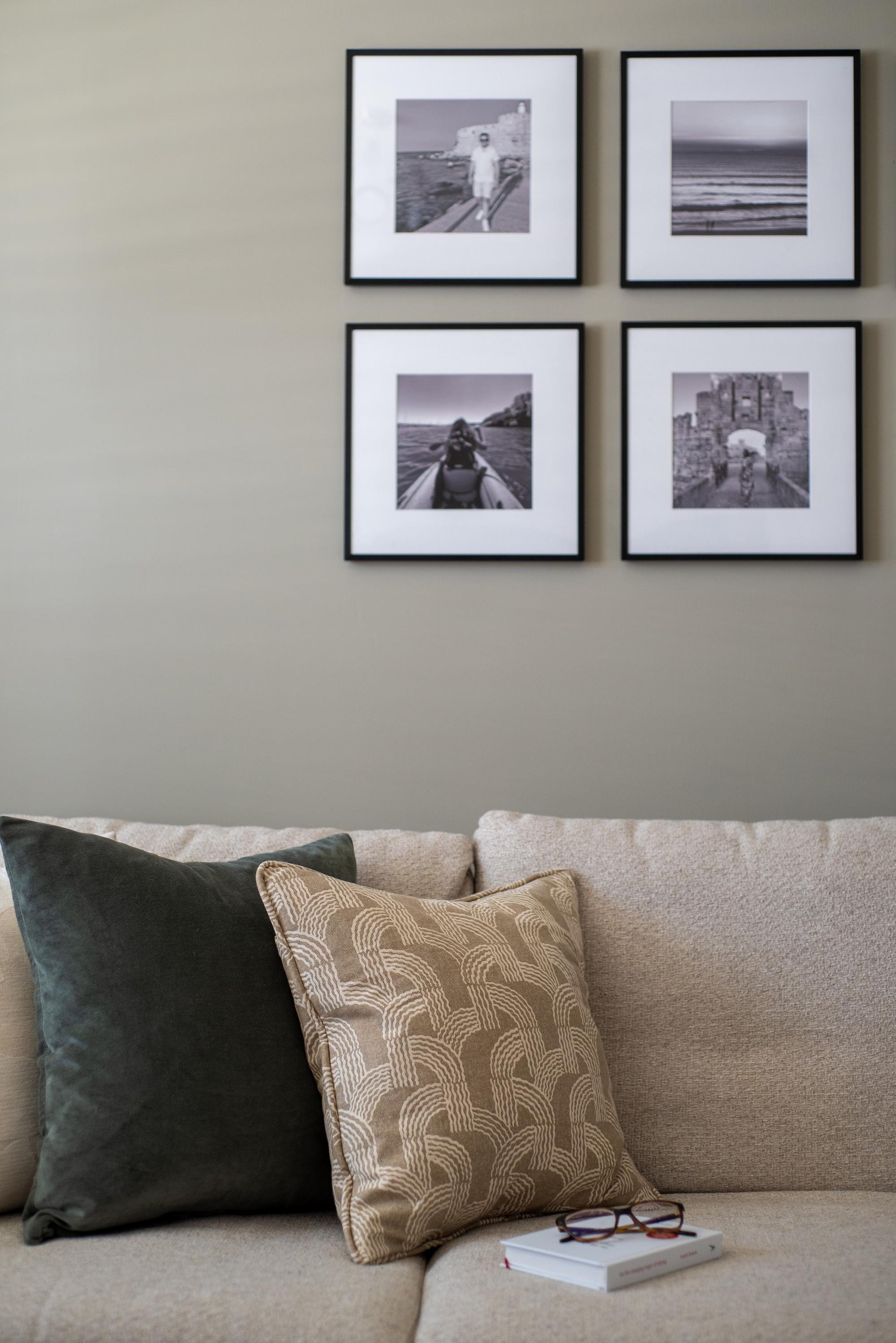 Black and White Gallery wall above neutral, linen sofa with patterned cushions.