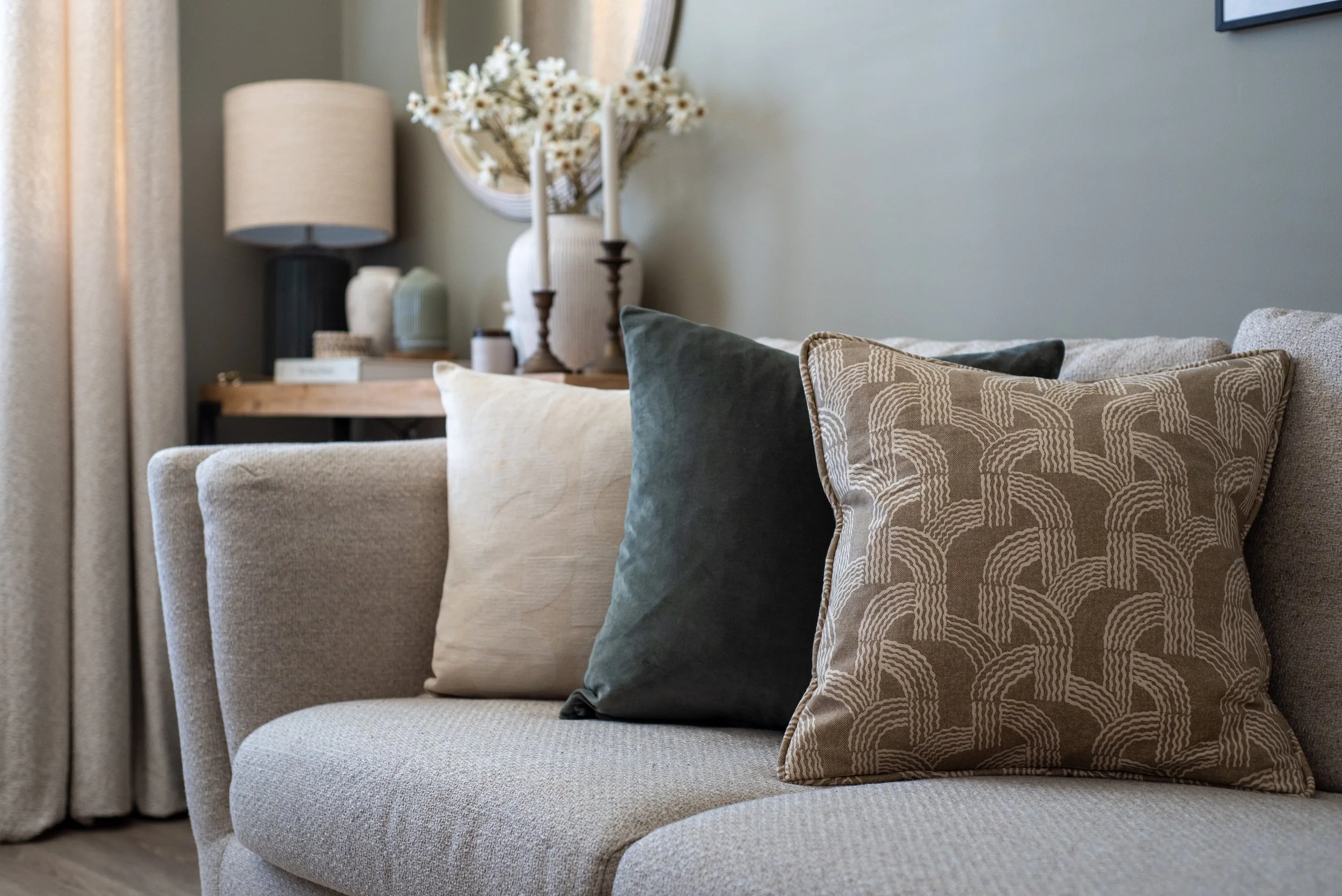 Cushions made from Fermoie fabric, layered on neutral, linen corner sofa.