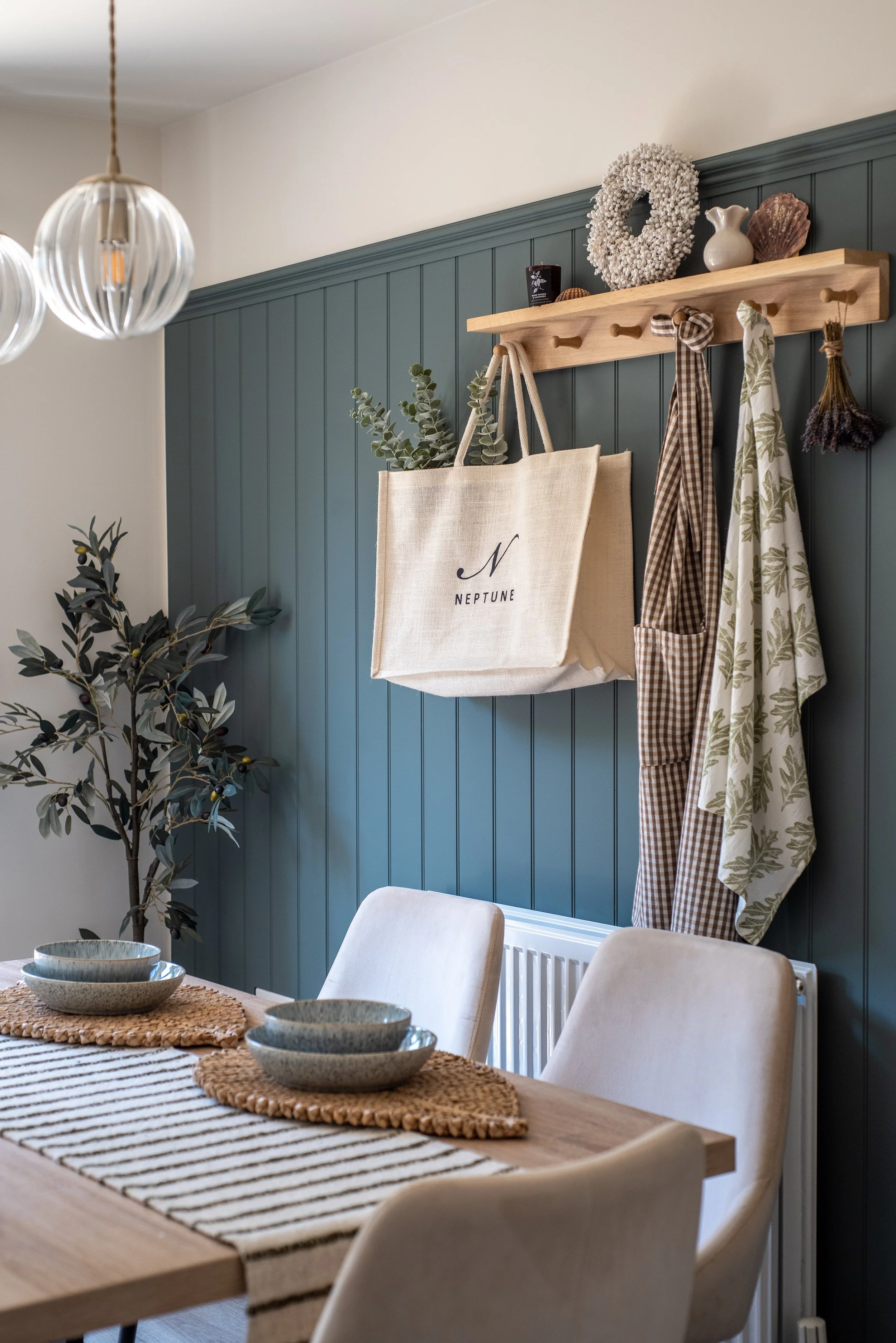 Countryside Dining area with deep teal panelling and wooden peg shelf styled with accessories.