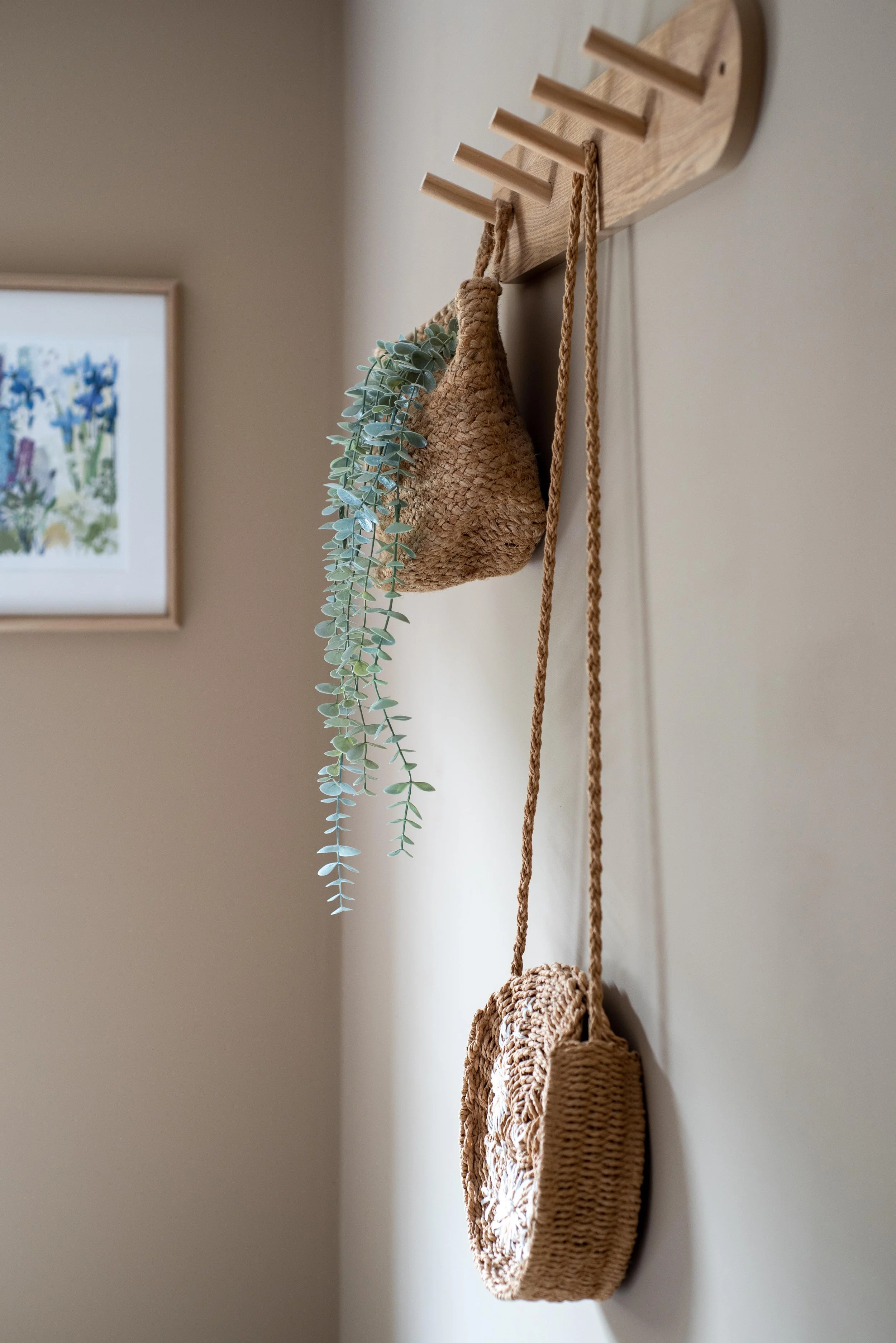 Oak peg hooks with rattan hangbag hanging and trailing faux plant.