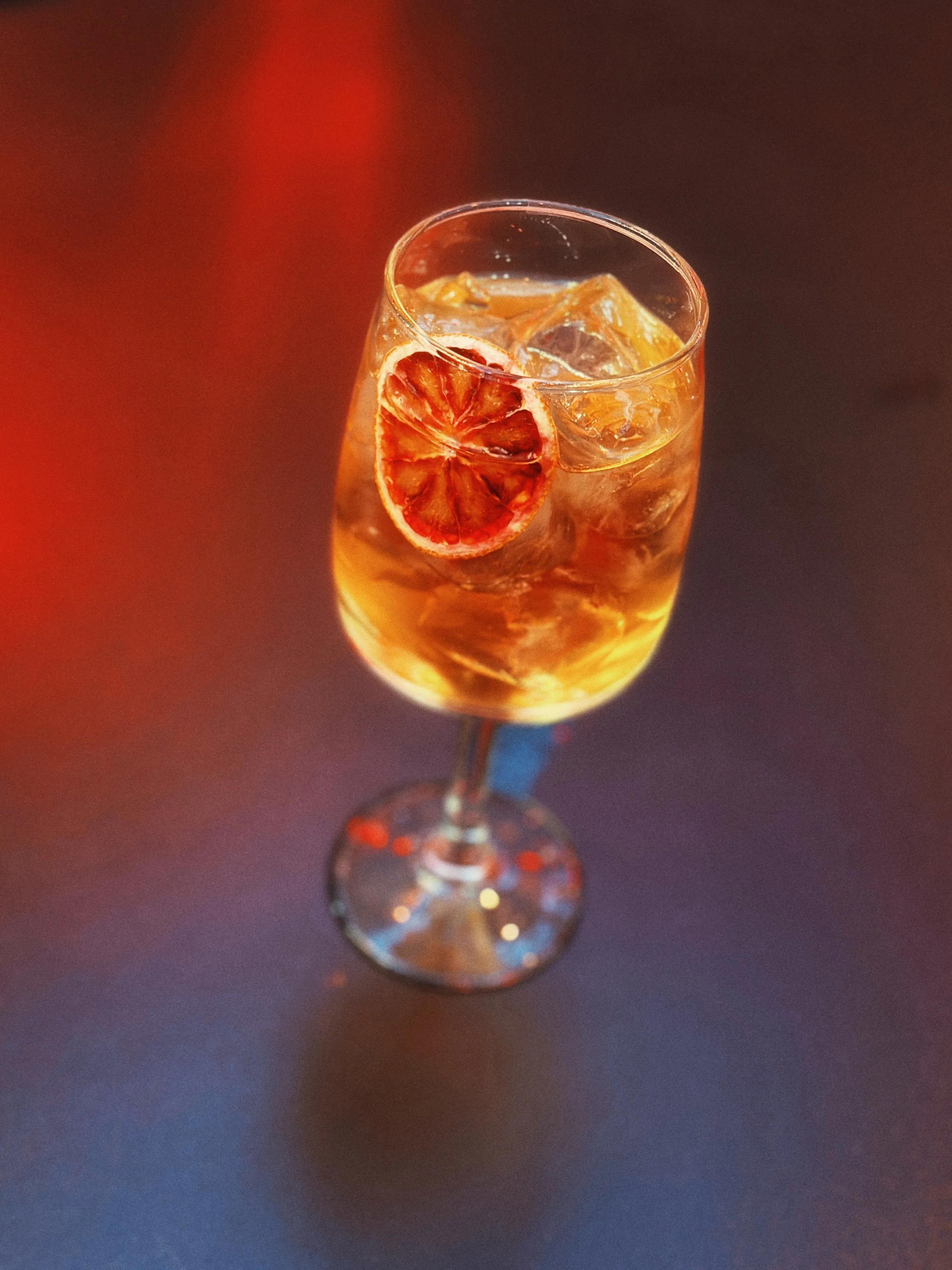 Un verre à vin avec des glaçons, une tranche de citron ou d'orange séchée, et une boisson ambrée