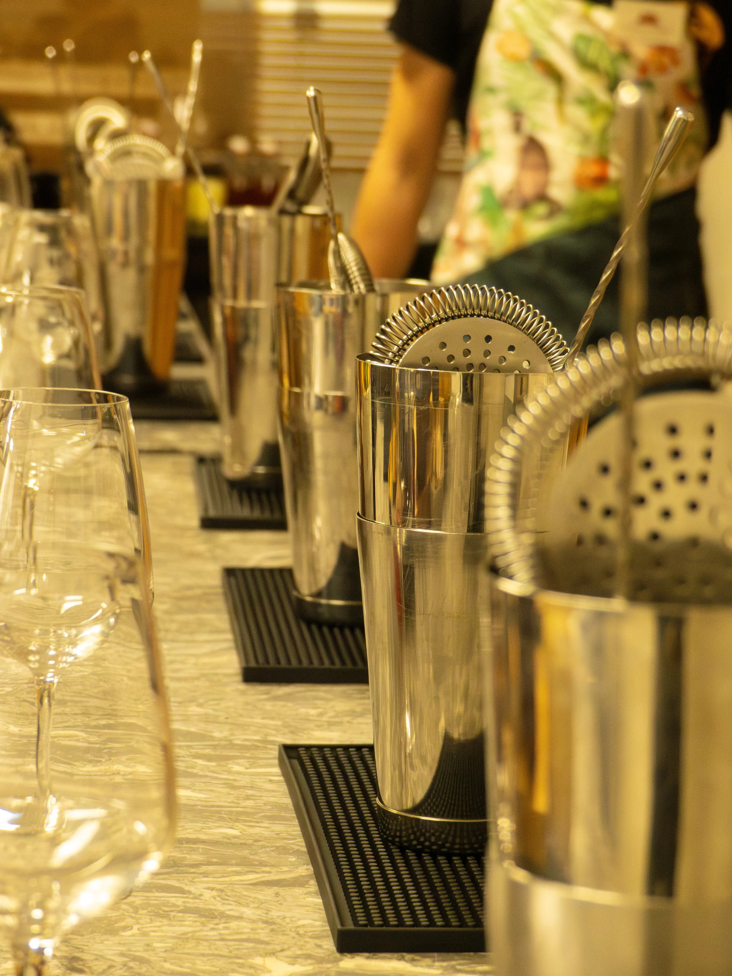 Coffrettes en acier inoxydable avec ustensiles de bar, verres à vin sur un comptoir en bois, environnement de bar ou de restaurant.
