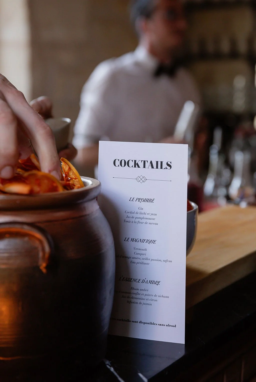 Sunset Spirit 2025, un menu de cocktails dans un bar, avec un barman en arrière-plan.