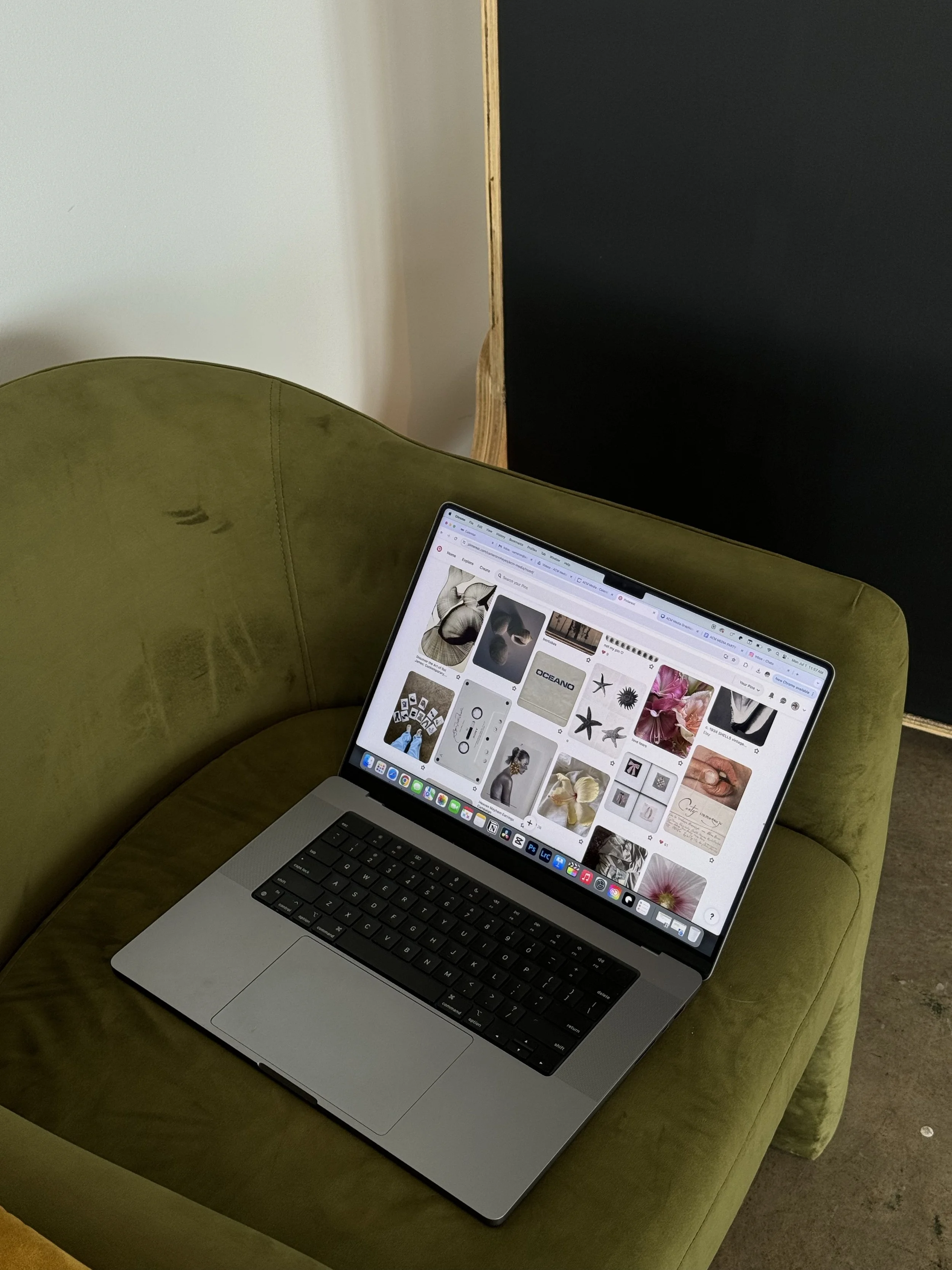 Laptop on green velvet armchair displaying a Pinterest page with various images of flowers, animals, and abstract art.