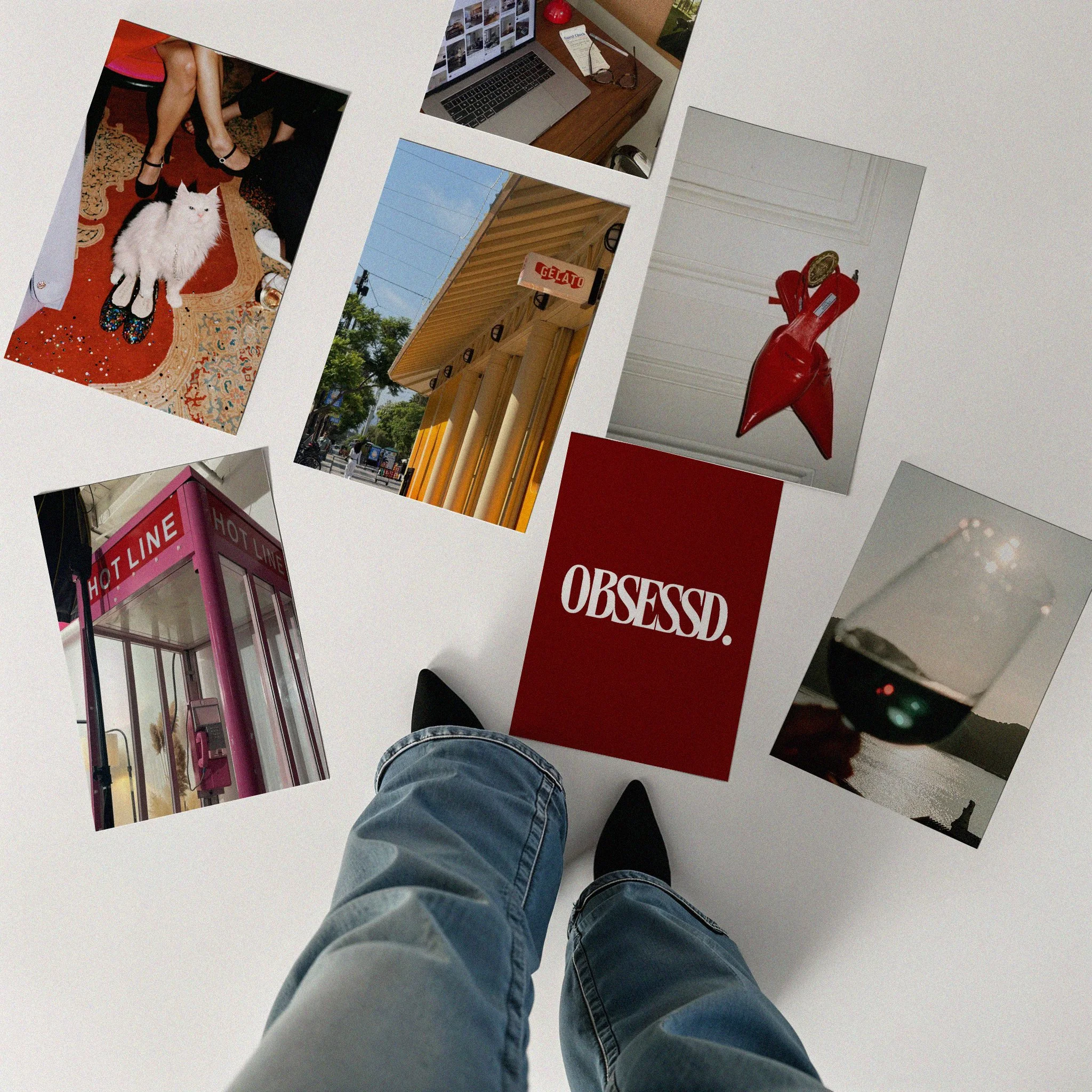 Photos spread on the floor showing a cat, a laptop, a gelato shop, a red high heel shoe, a pink phone booth, an artwork with the word "OBSESSD", and a glass of red wine, with person wearing jeans and black shoes standing in the center.
