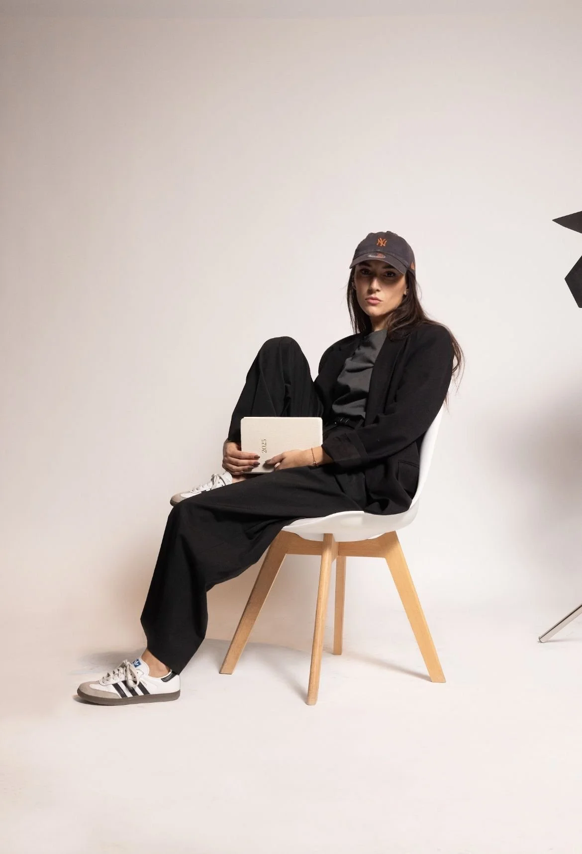 Donna con capelli lunghi e sciolti, indossa abbigliamento elegante nero, sorride in posa su sfondo neutro.