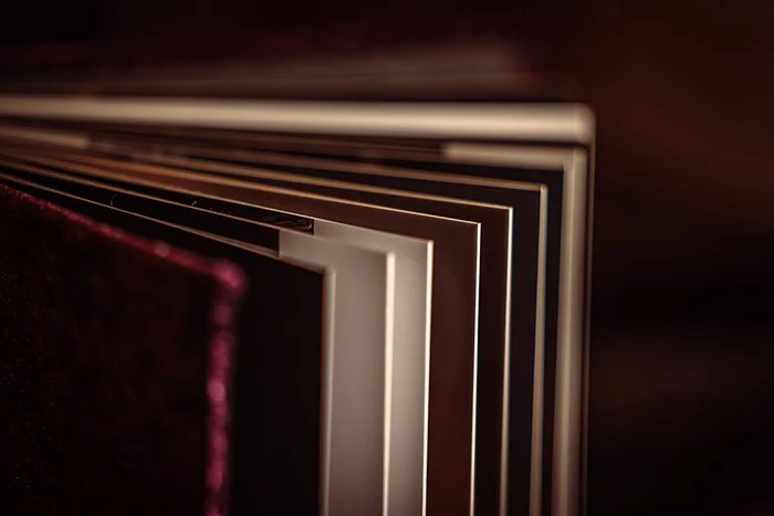 Close-up of pages in a hardcover book or photo album with dark and light-colored edges.