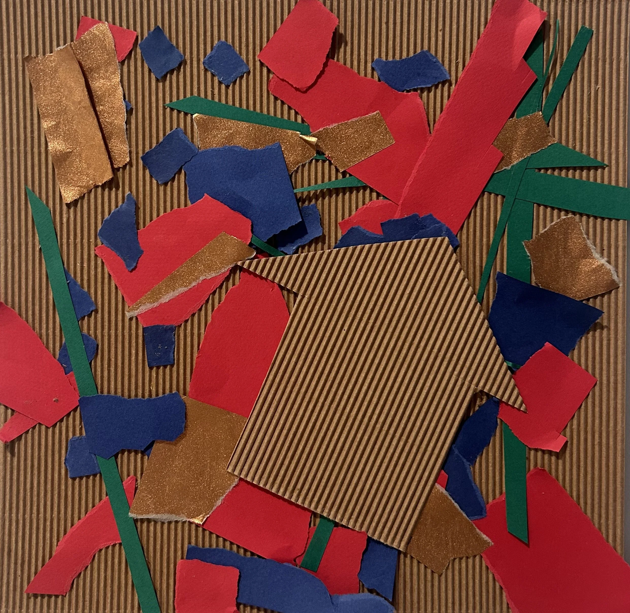 Colorful torn paper pieces including red, blue, green, and gold, scattered on a corrugated cardboard surface.