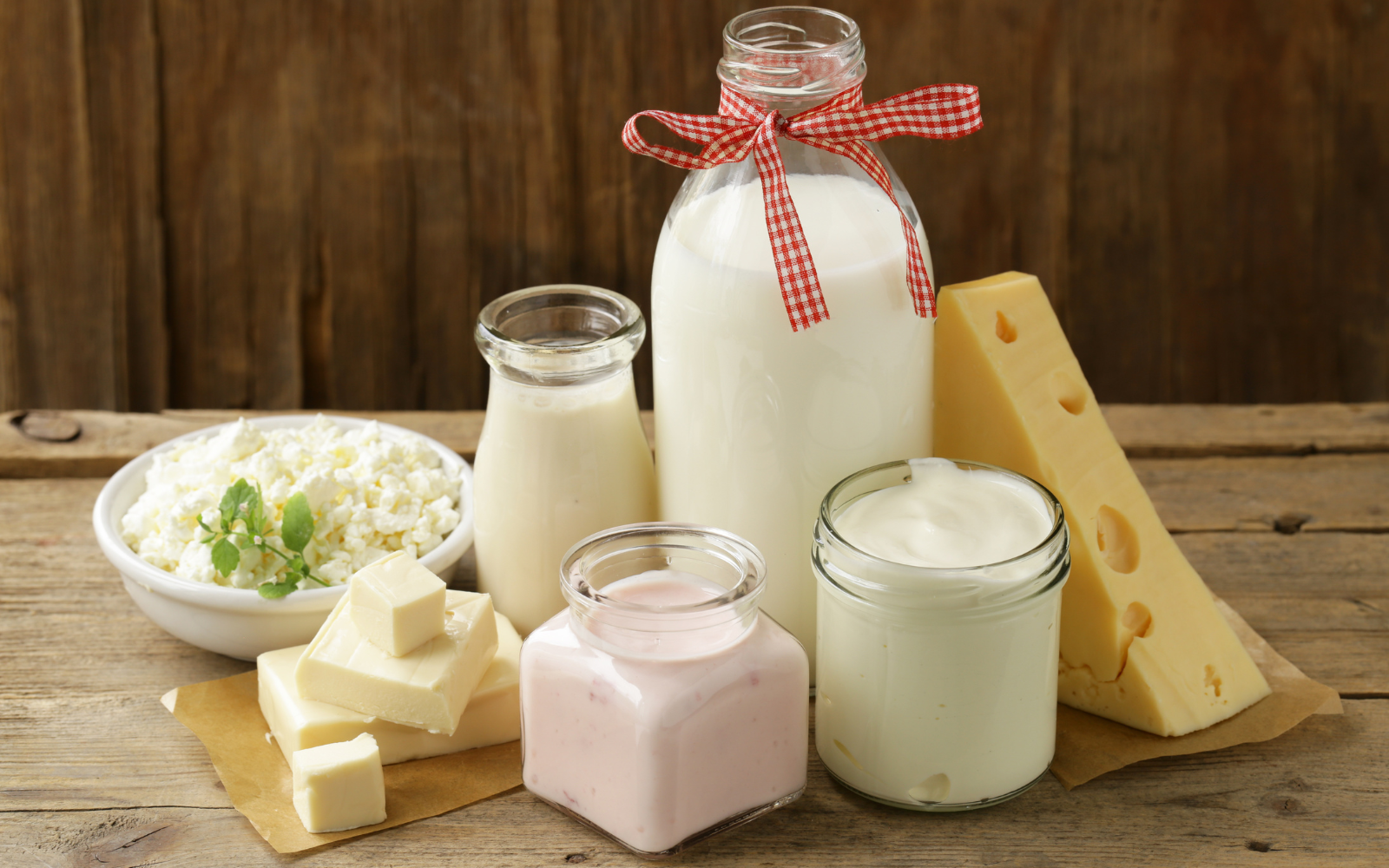 Various types of cheese, milk, cream, and yogurt displayed on a wooden surface.