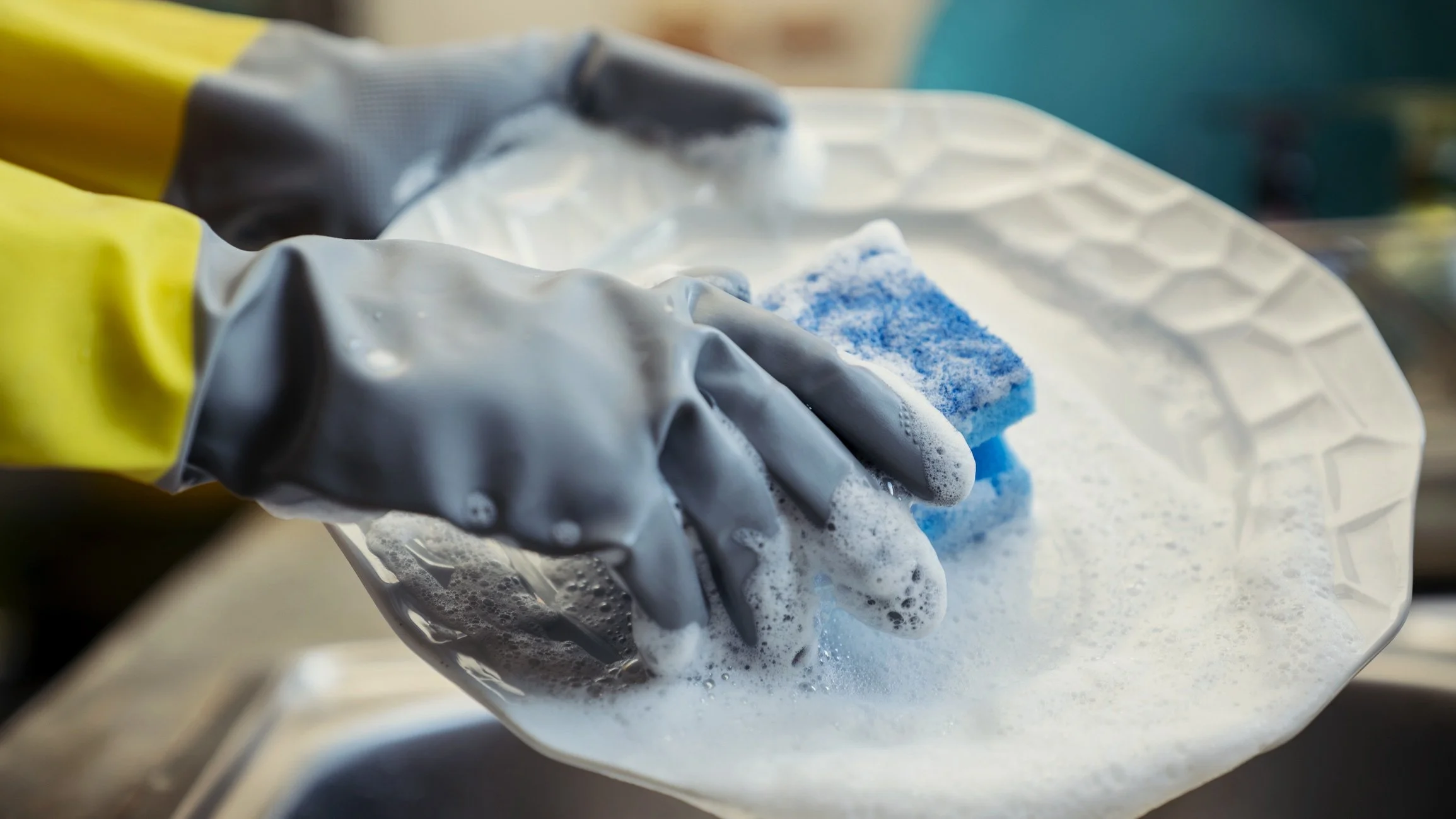 washing dished with a sponge and rubber gloves