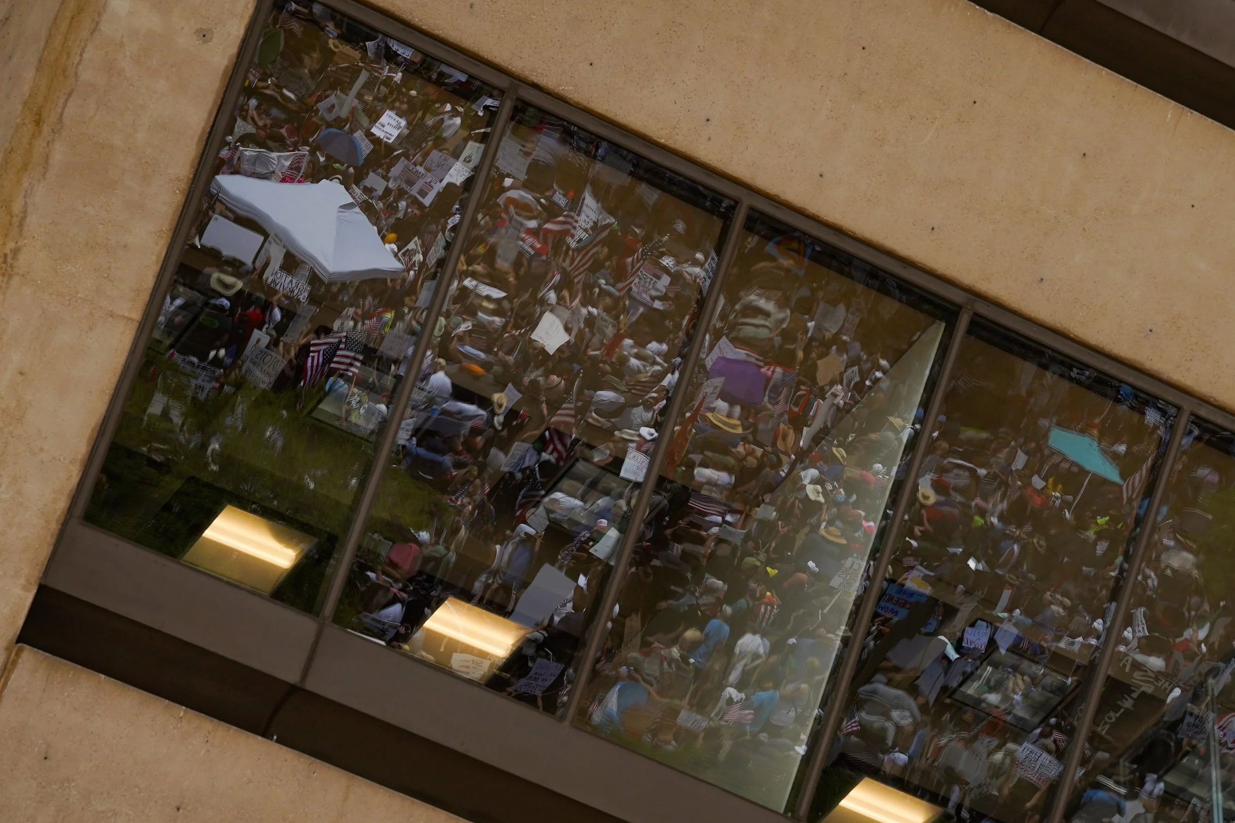 Reflections of demonstrators can be seen in the windows of Dallas City Hall during the national No-Kings Day protest in Dallas, Texas June 14, 2025.