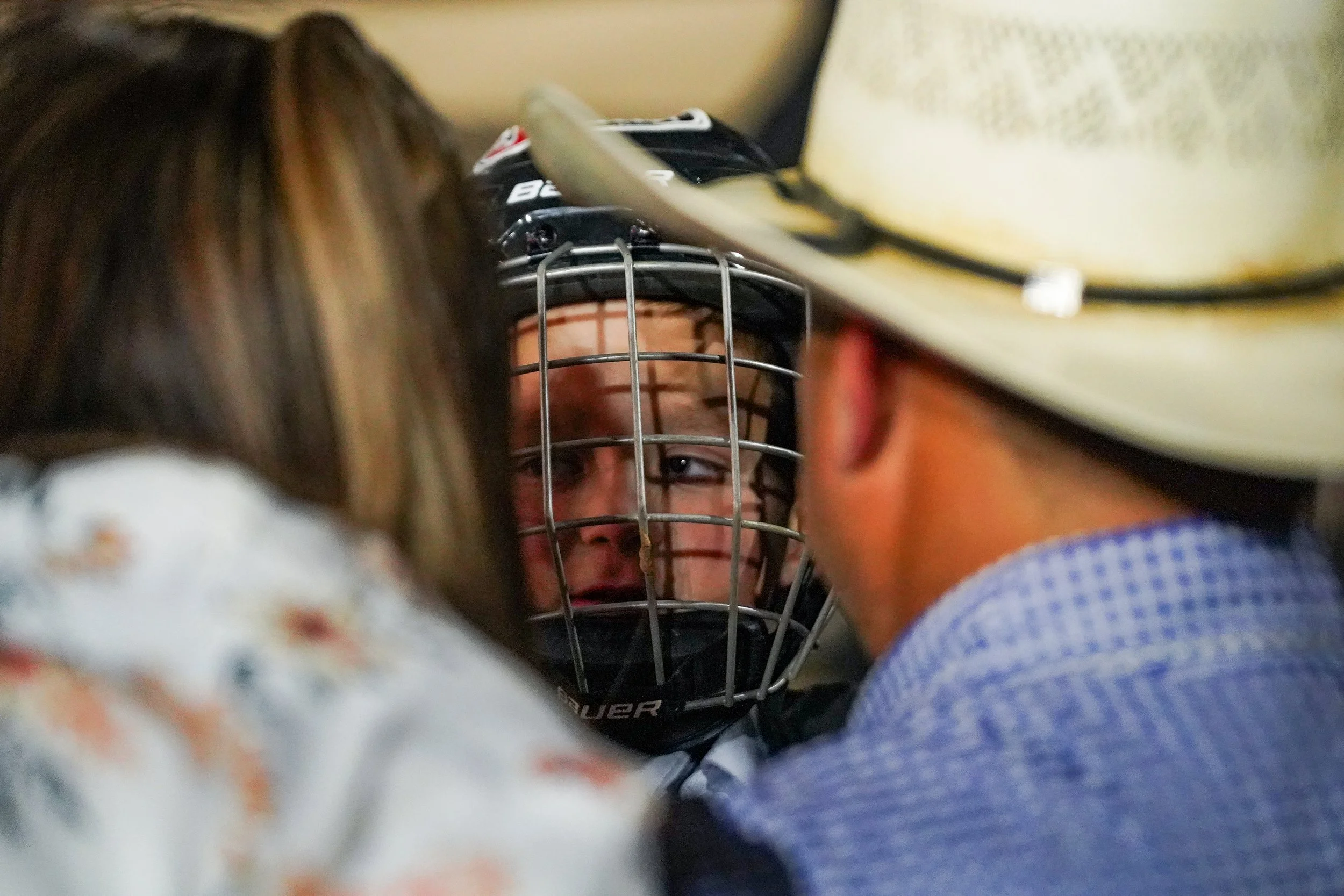 A young boy trades looks with his parents through a mutton busting helmet during the Parker County Sheriffs Posse Rodeo hosted at the PCSP Rodeo Arena in Weatherford, Texas June 13, 2025.