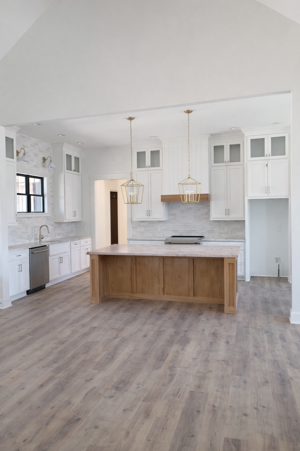 Modern kitchen with white cabinets, granite countertops, a central island with a sink, and pendant lighting fixtures.