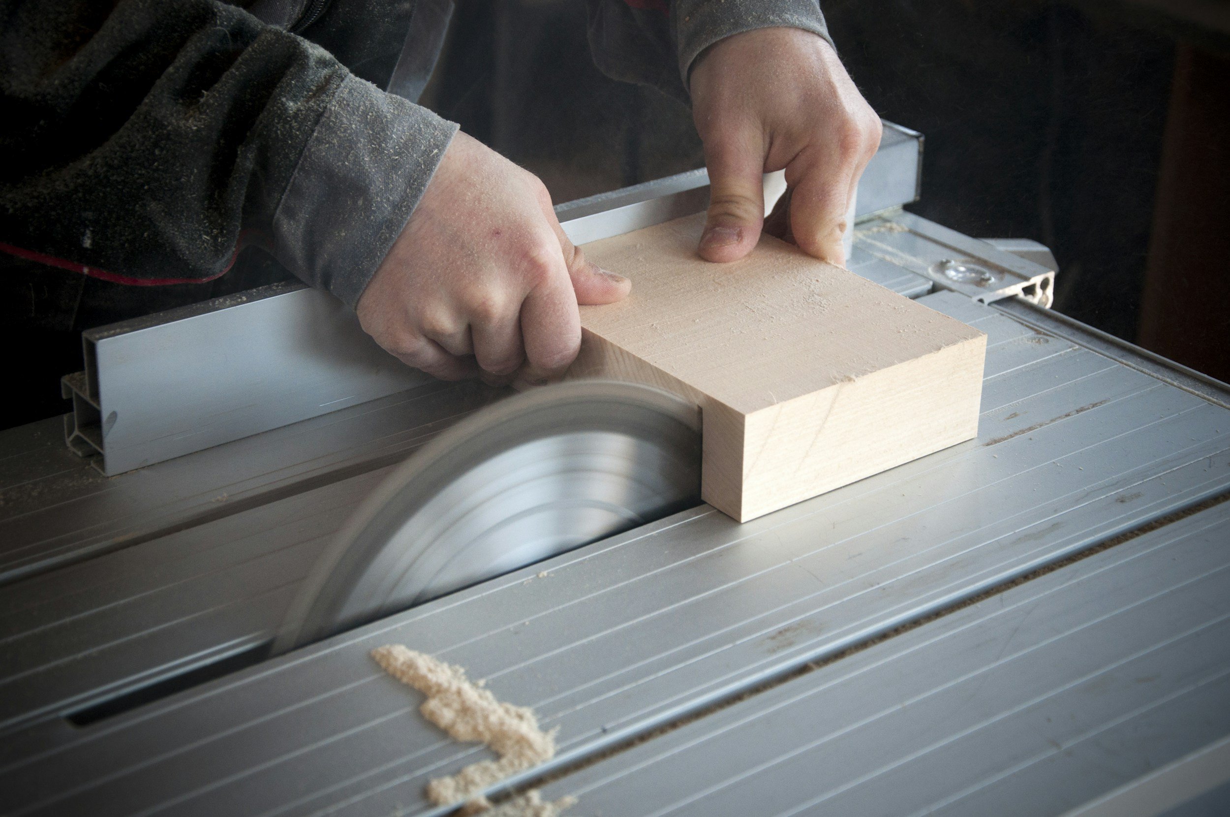 Person using a circular saw to cut a wooden block on a table saw.