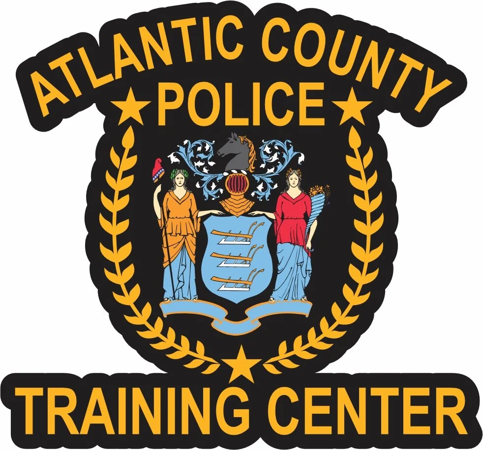 Badge of Atlantic County Police Training Center with the county seal in the center featuring two women, shields, and decorative elements, surrounded by a yellow laurel wreath and text.