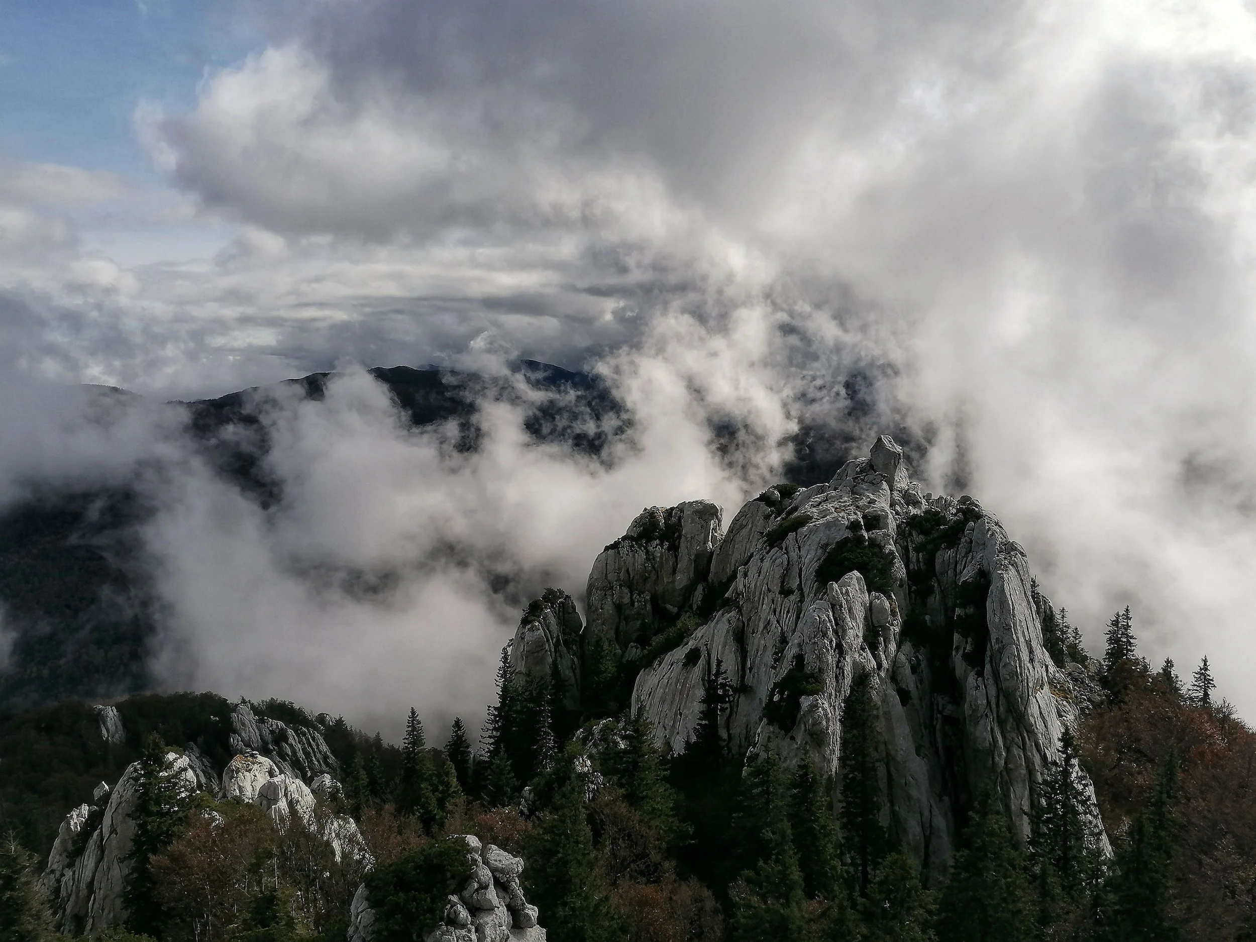 A cloud-wreathed mountain peak rising into mist, black and white.