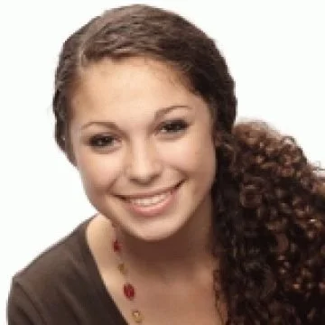 Portrait of a young woman with curly hair smiling against a white background.