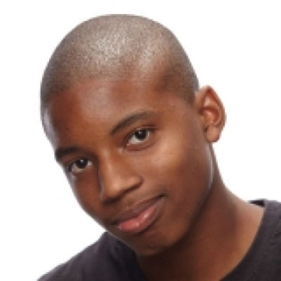 Portrait of a young man with a shaved head and a slight smile wearing a dark shirt.