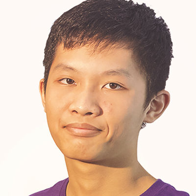 Young person with short black hair and a neutral expression, wearing a purple shirt, facing the camera in a studio setting.