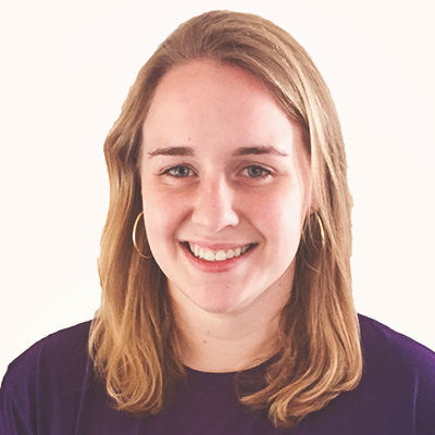 A young woman with shoulder-length light brown hair, wearing a dark purple top, smiling at the camera against a plain white background.