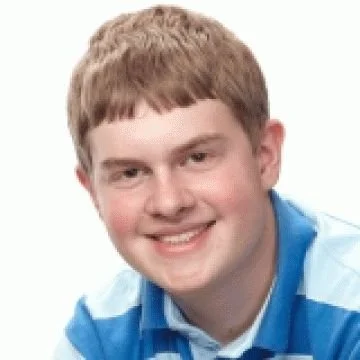 A smiling young man with short, light brown hair wearing a blue and white striped shirt, posing against a plain white background.