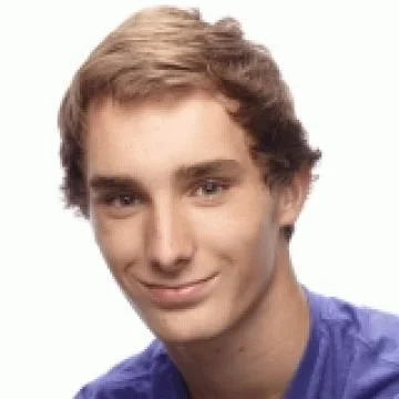 A young man with light brown hair smiling at the camera, wearing a blue shirt.