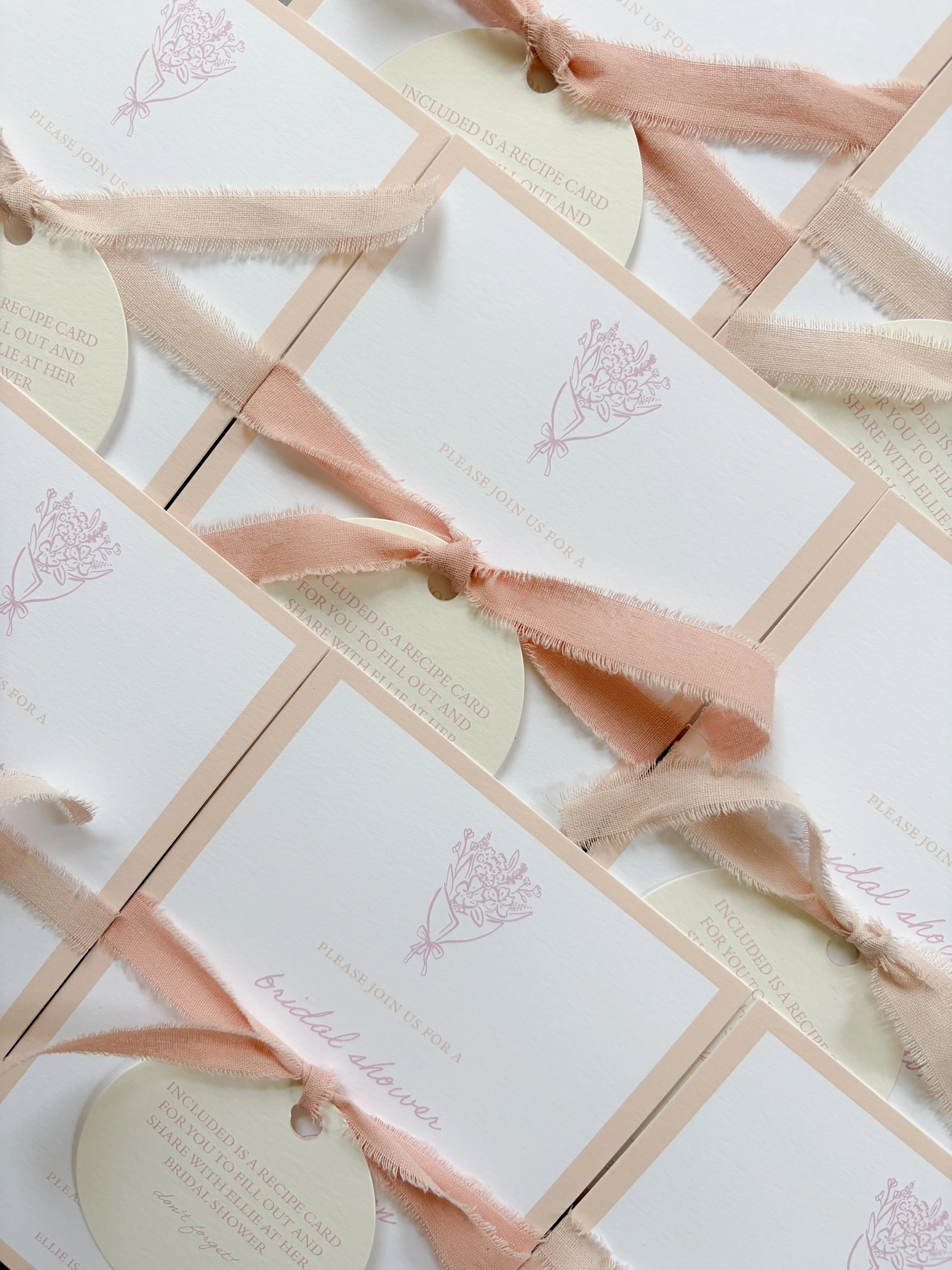 Multiple wedding invitation cards with pink ribbons and floral designs.