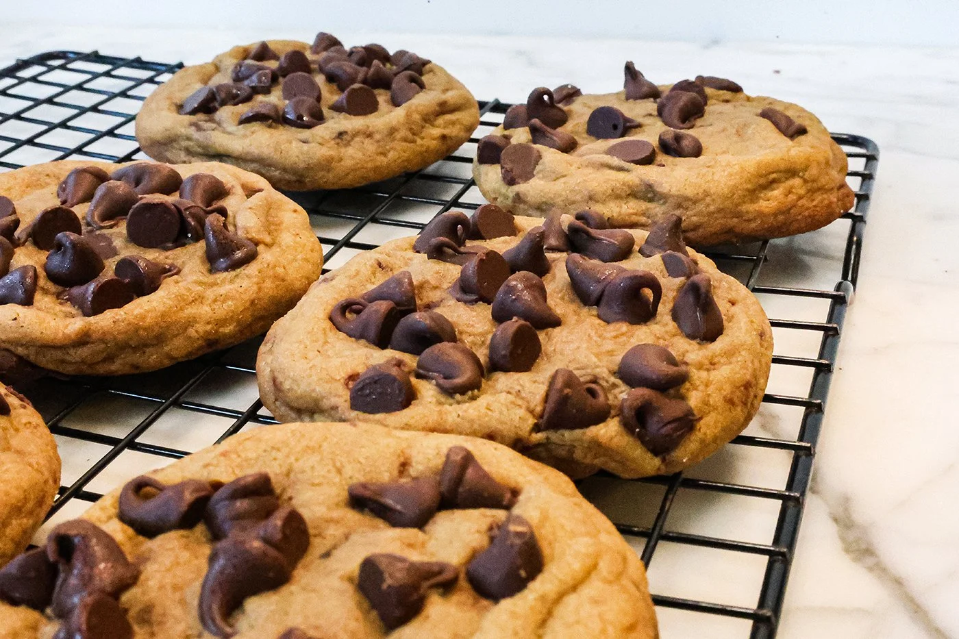 Freshly baked chocolate chip cookies on a cooling rack.