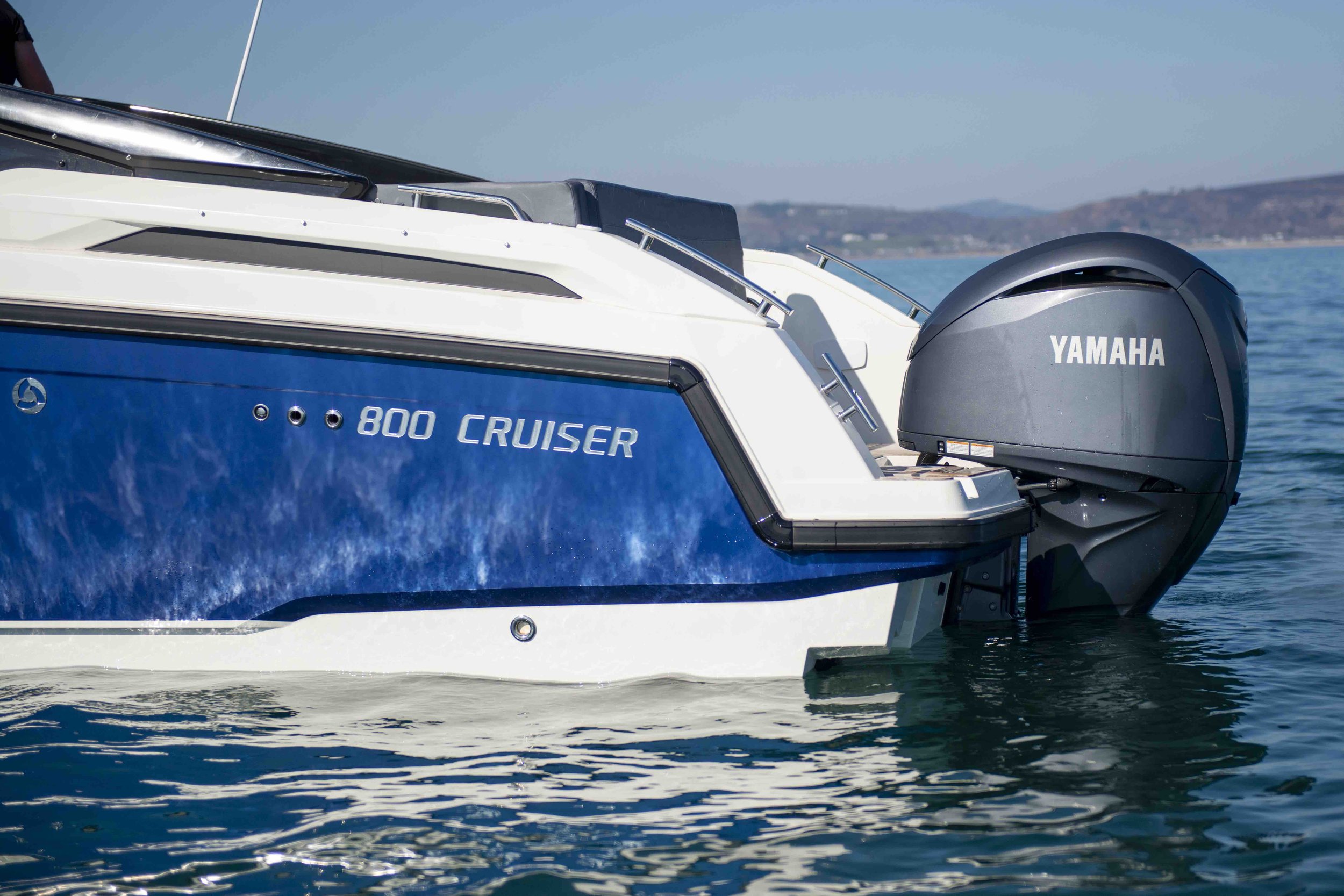 Side view of a blue and white powerboat labeled '800 Cruiser' with a Yamaha outboard motor, floating on water.