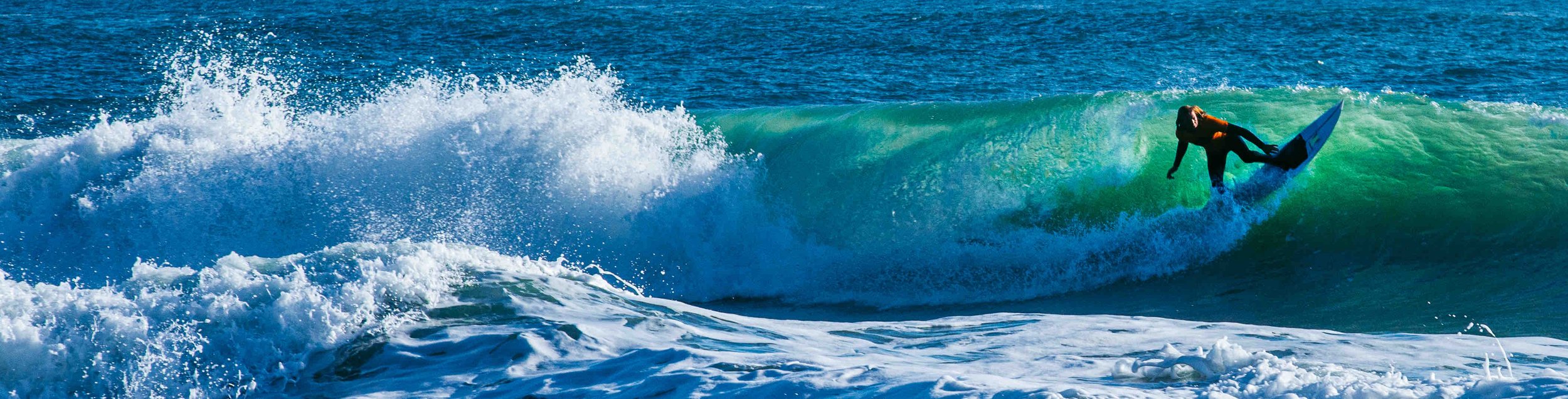 Surfer riding a wave in the ocean, with water splashing around.