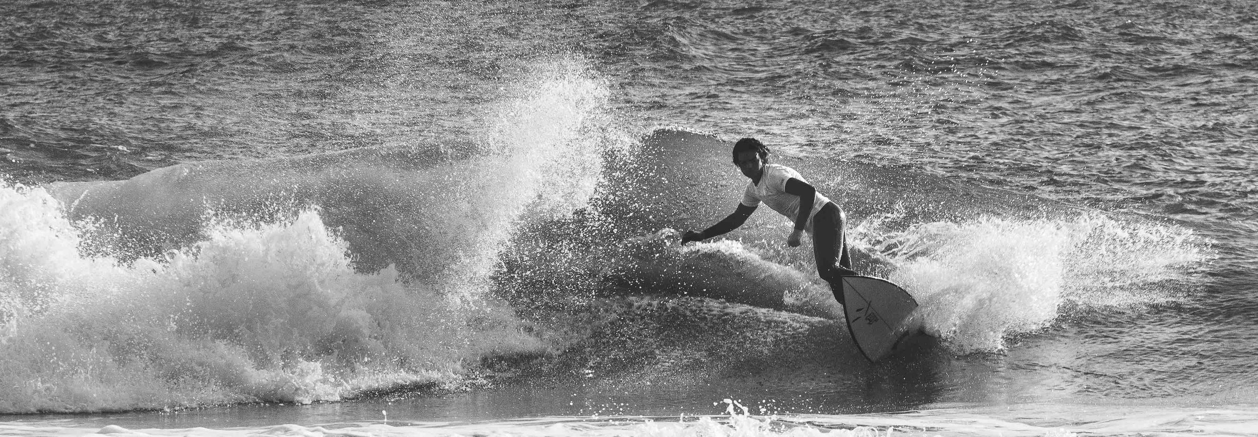 Black and white photo of a surfer riding a wave.