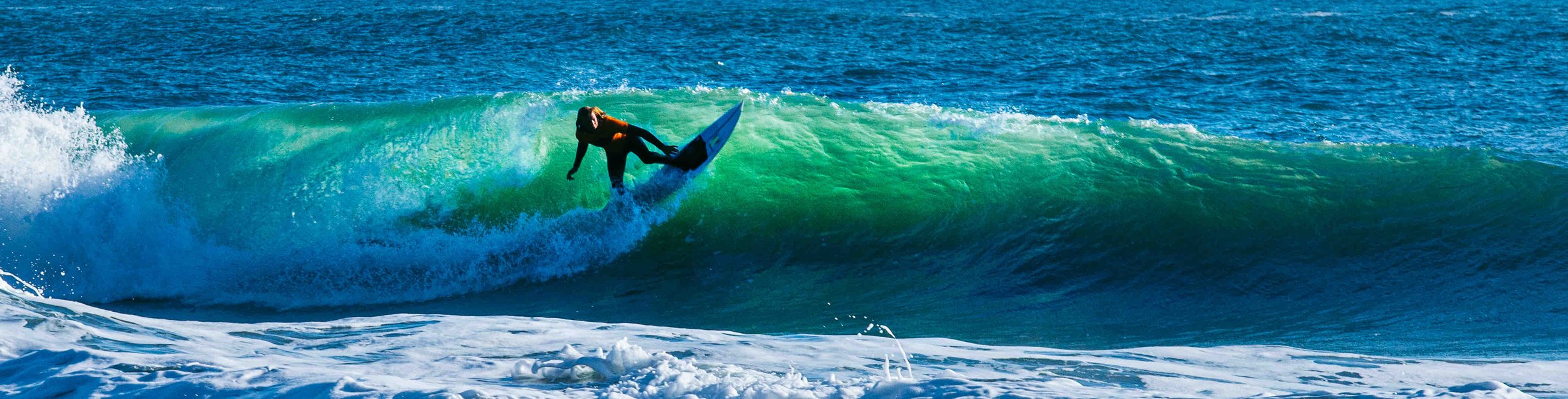 Surfer riding a large green wave in the ocean.