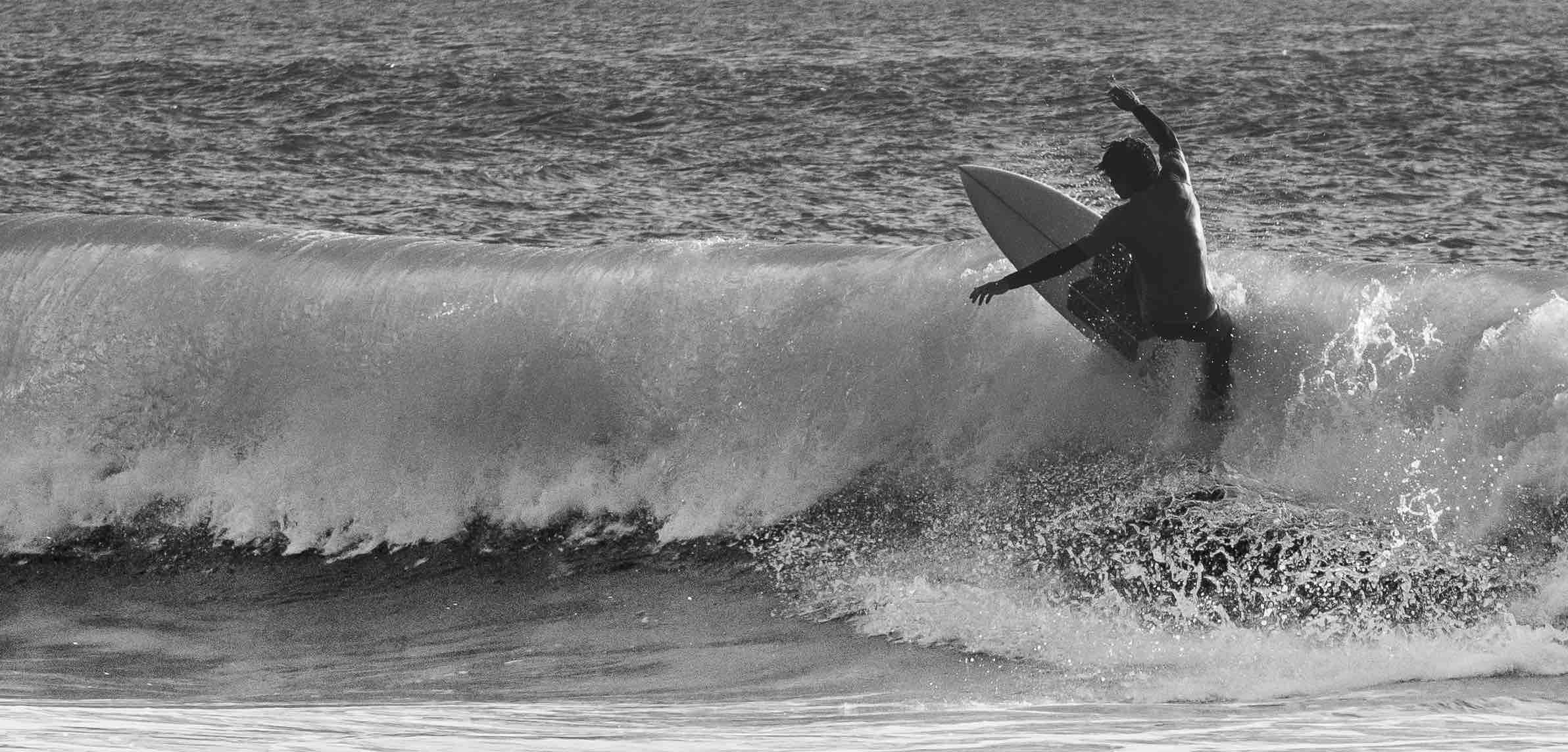 Black and white photo of a surfer riding a wave
