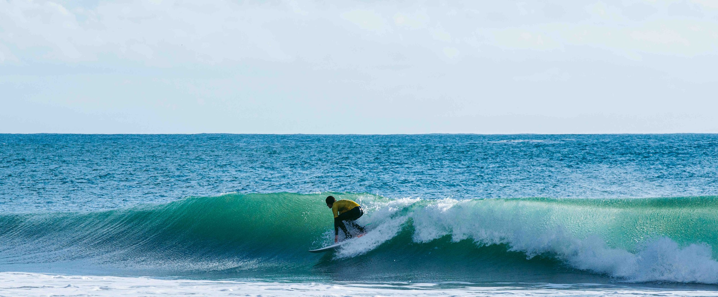 Surfer in yellow shirt riding a wave in the ocean