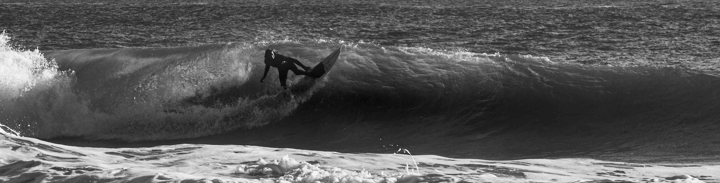 Surfer riding a large wave in black and white