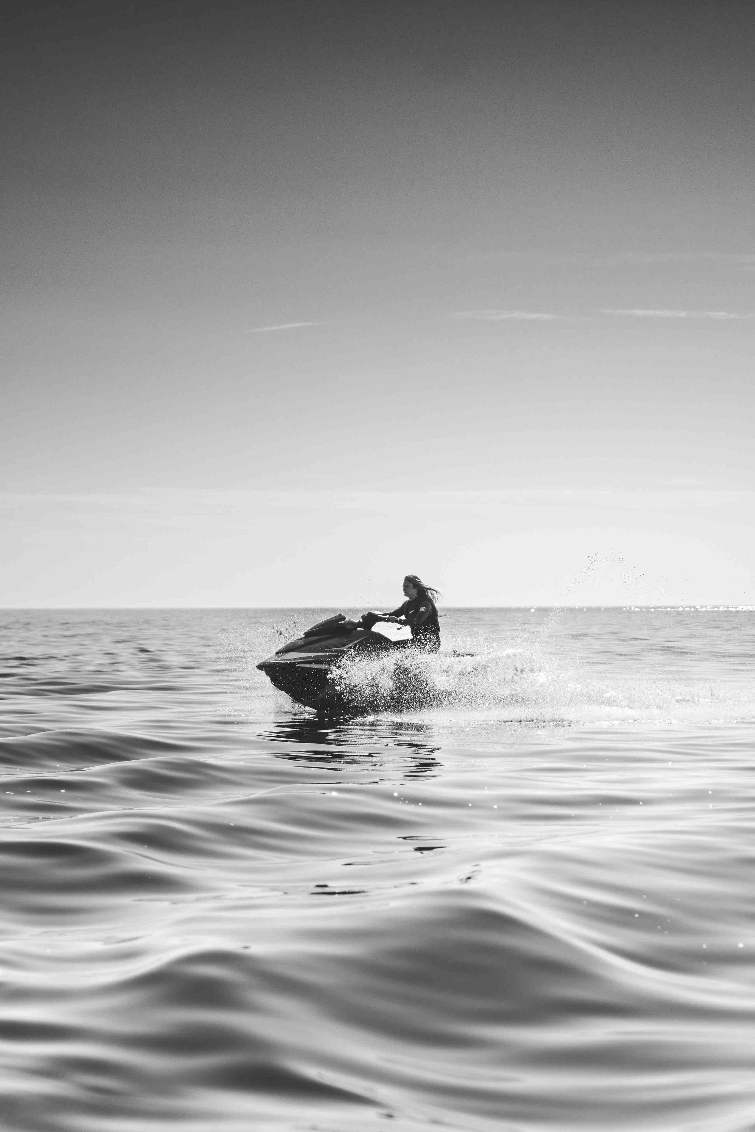 Person riding a jet ski on open water in black and white