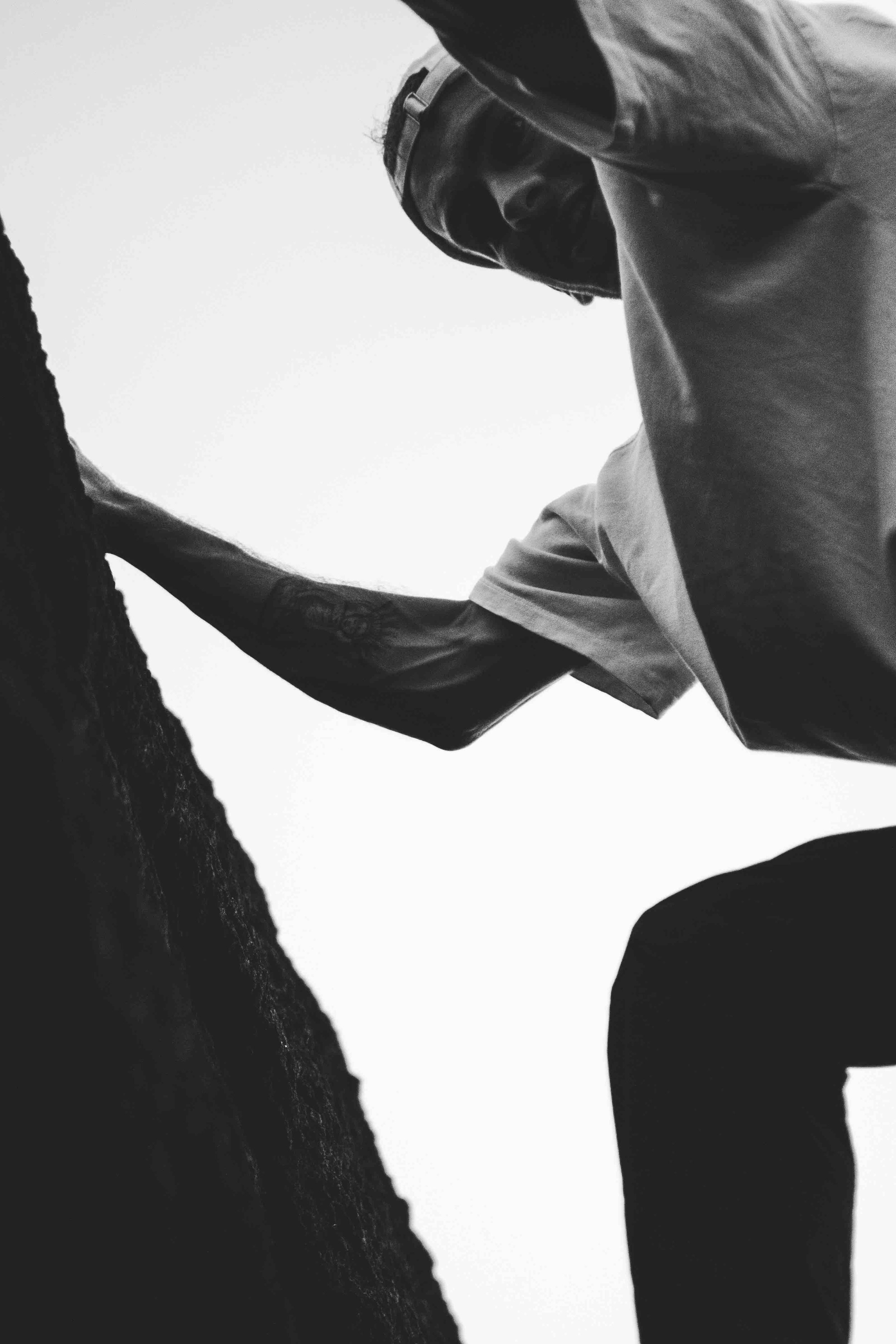 Black and white photo of a person climbing a rock face.