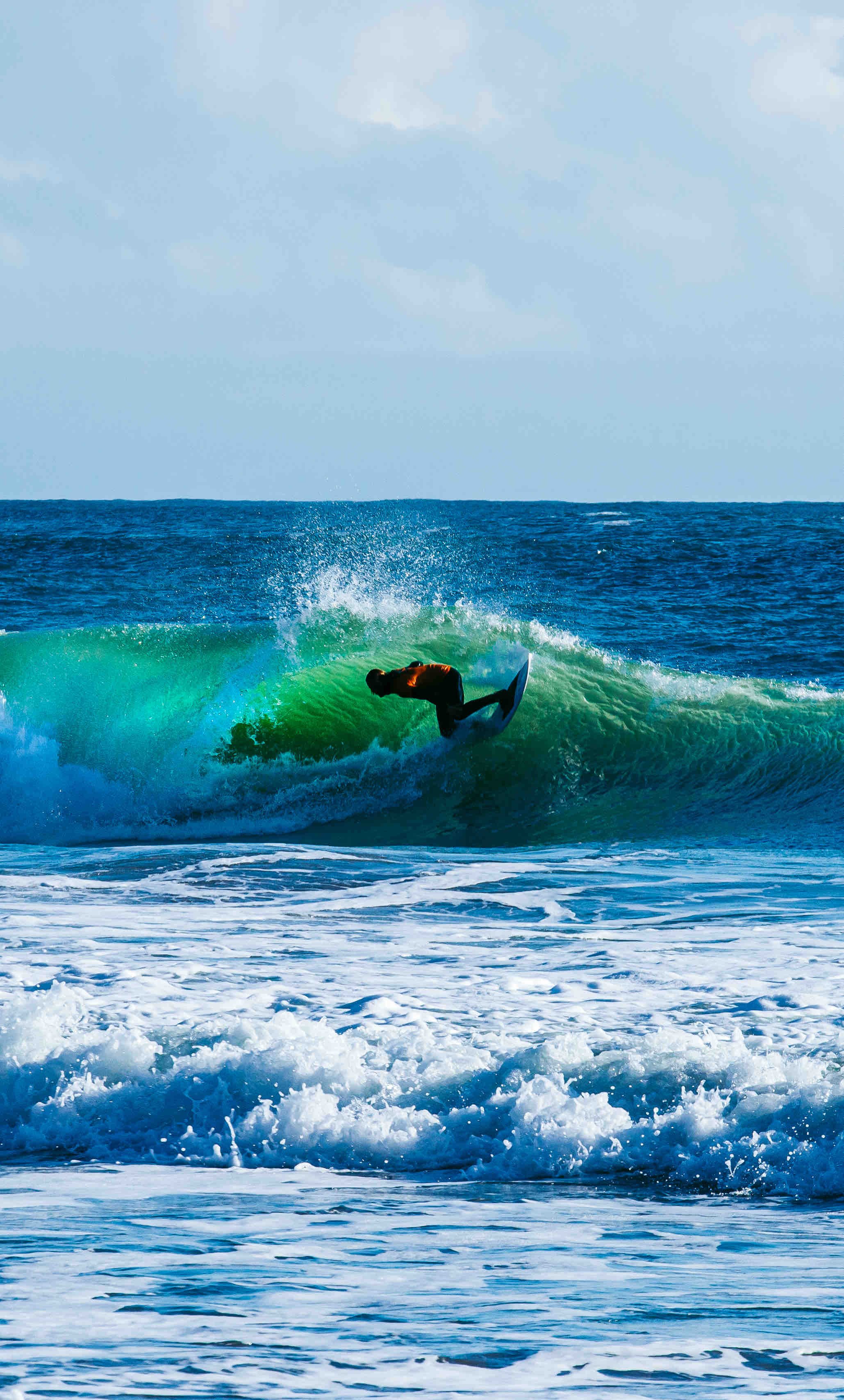 Surfer riding a wave in the ocean on a sunny day.