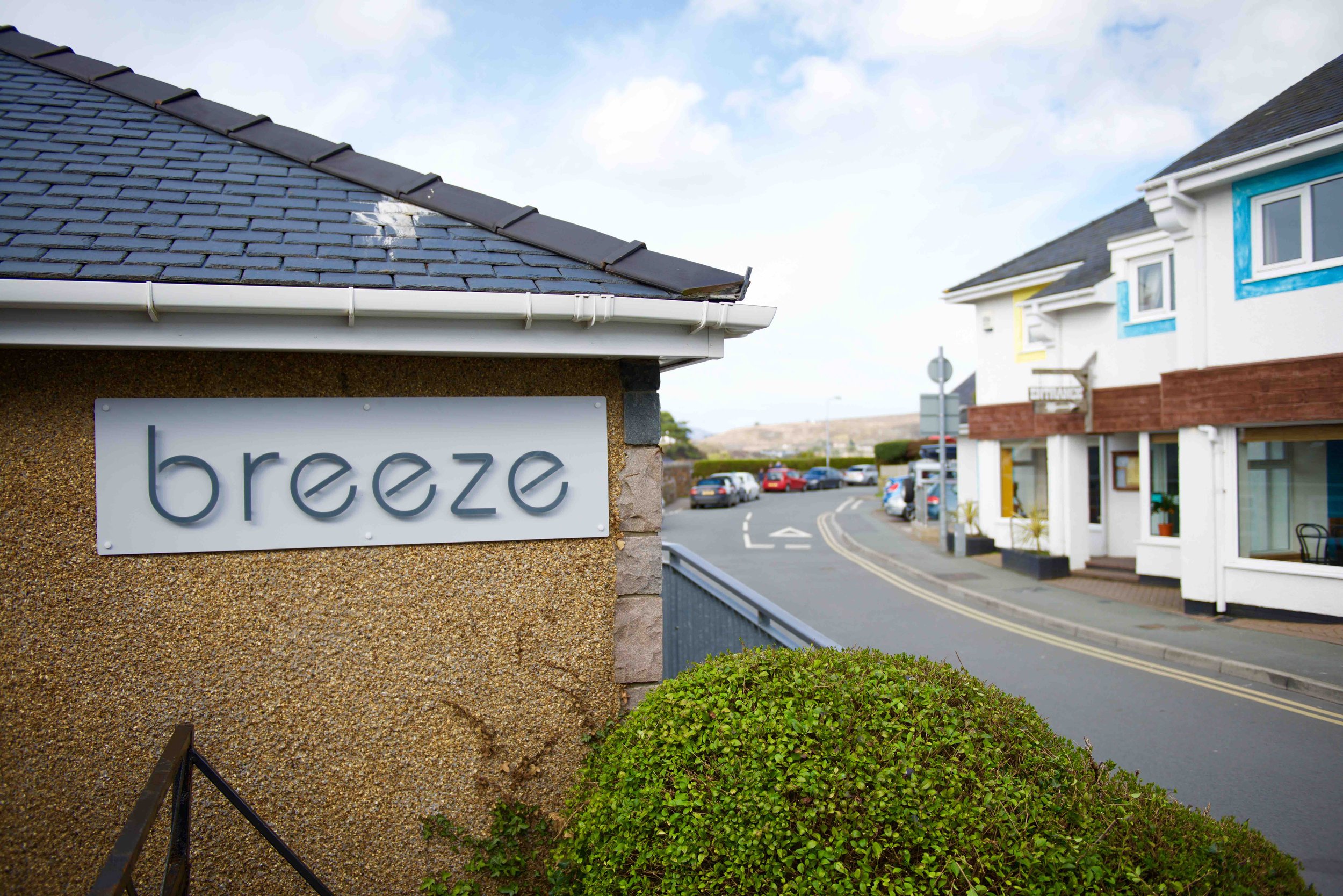 Building with a sign reading 'breeze' and a view of a street with cars and buildings in the background.